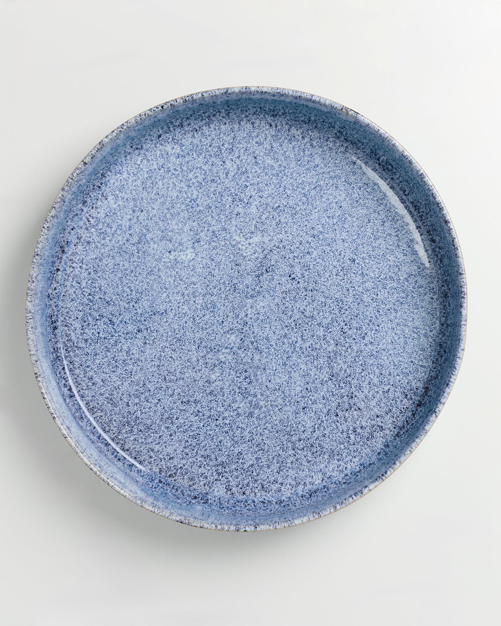 Blauer, strukturierter Keramikteller auf weißem Hintergrund.