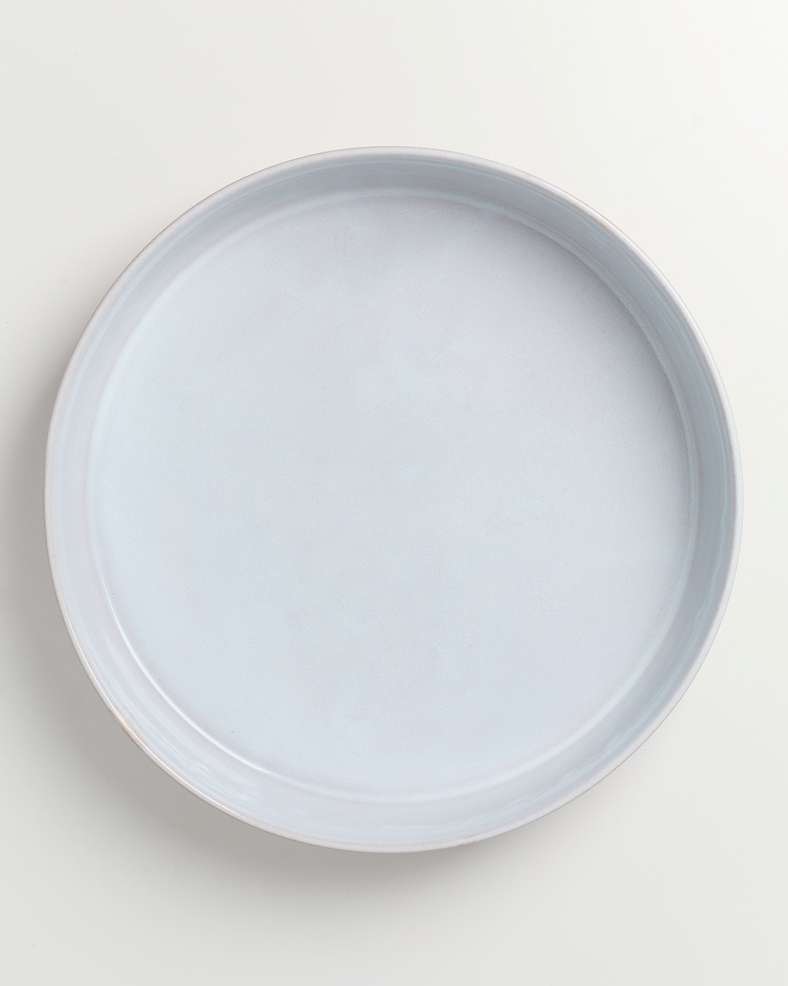 Ein leerer, runder, hellgrauer Teller auf einem weißen Hintergrund.