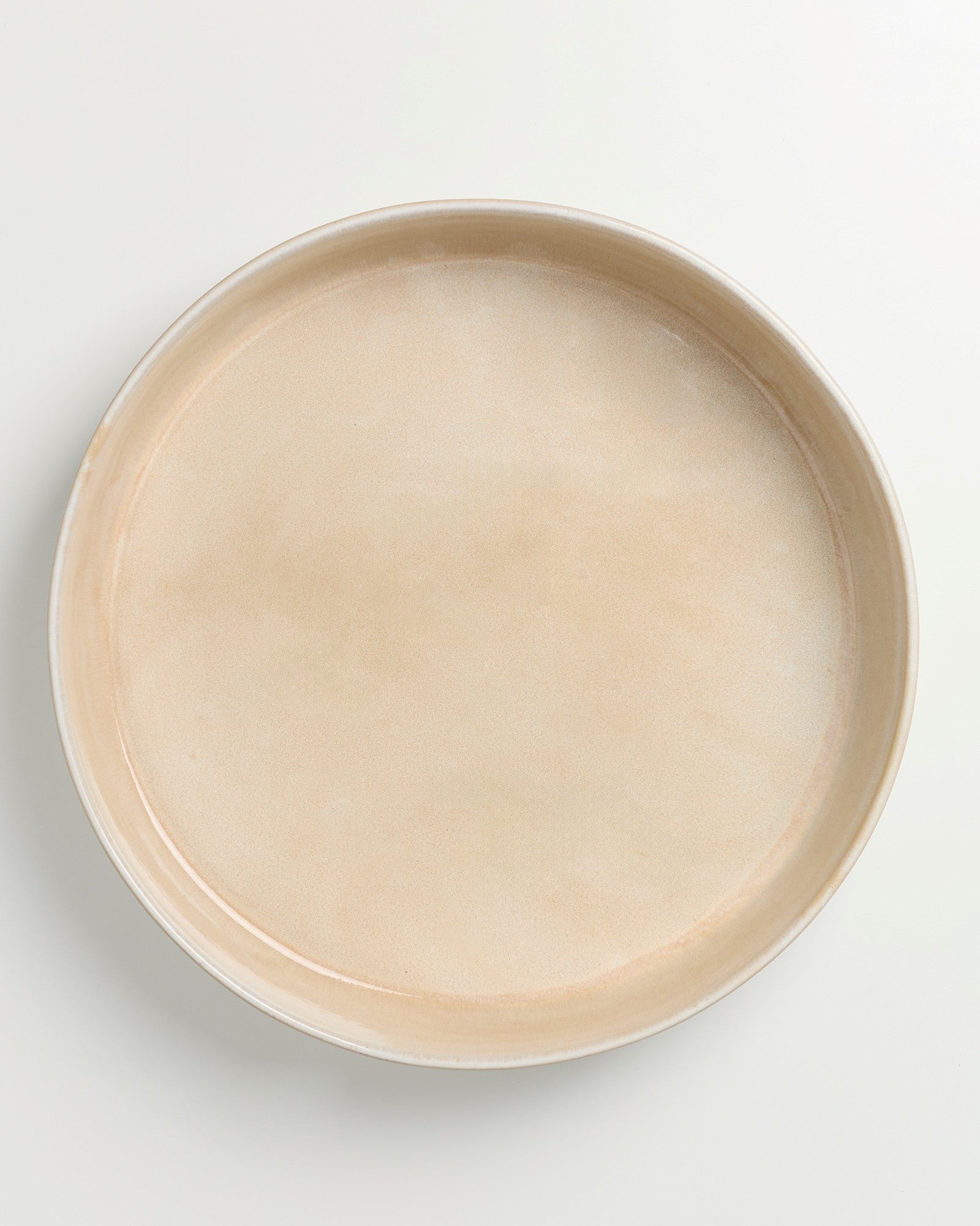 Beiger Keramikteller auf weißem Hintergrund.