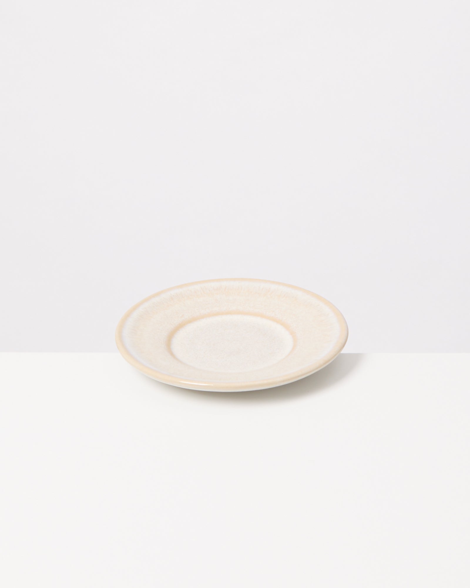 Beiger, runder Teller auf weißem Hintergrund.