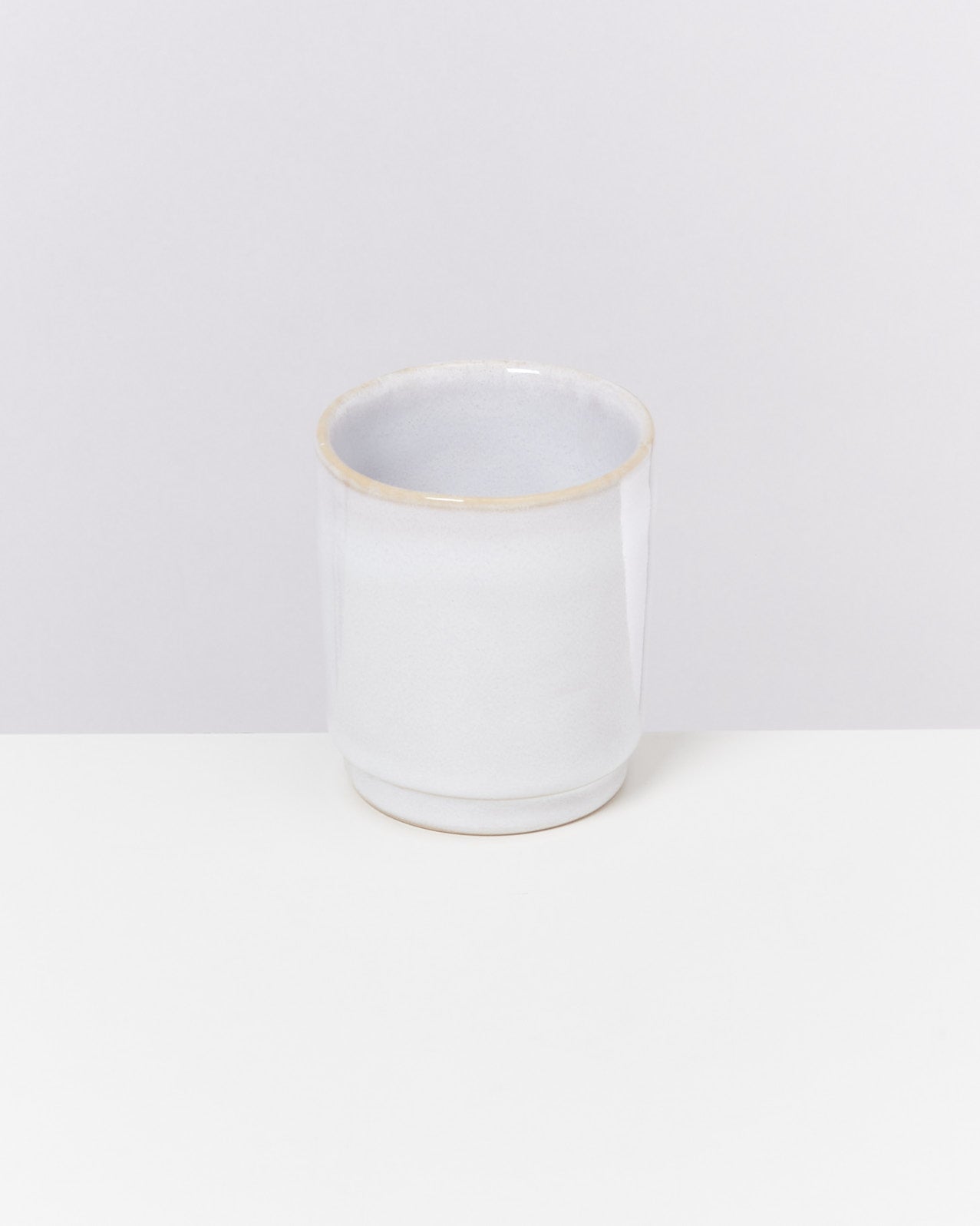 Weißer Keramikbecher mit glatter Oberfläche auf einem weißen Hintergrund.