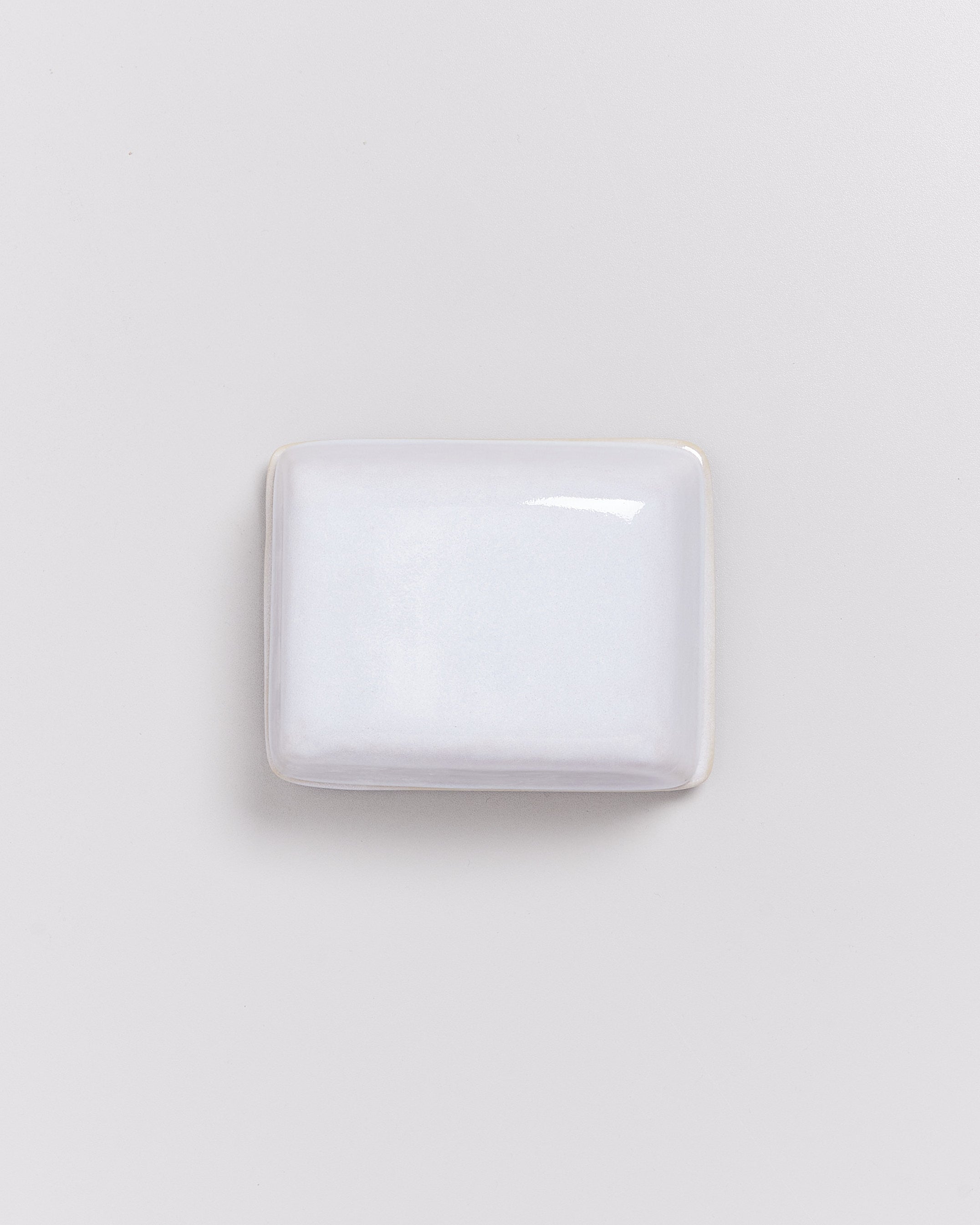 Rechteckige, glänzende, weiße Seife auf einem hellgrauen Hintergrund.