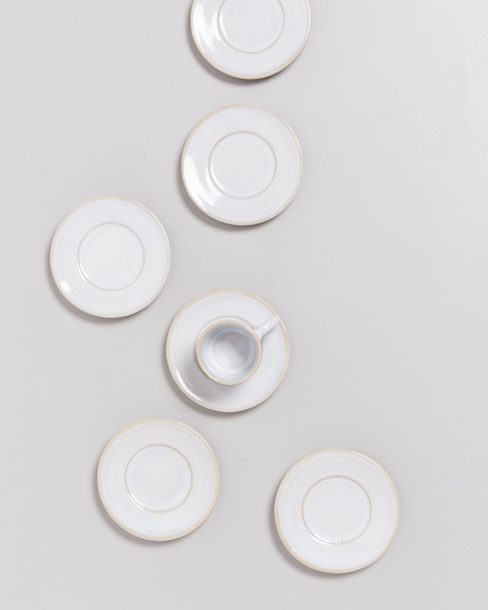 Weiße Untertassen und eine Tasse auf hellem Hintergrund.