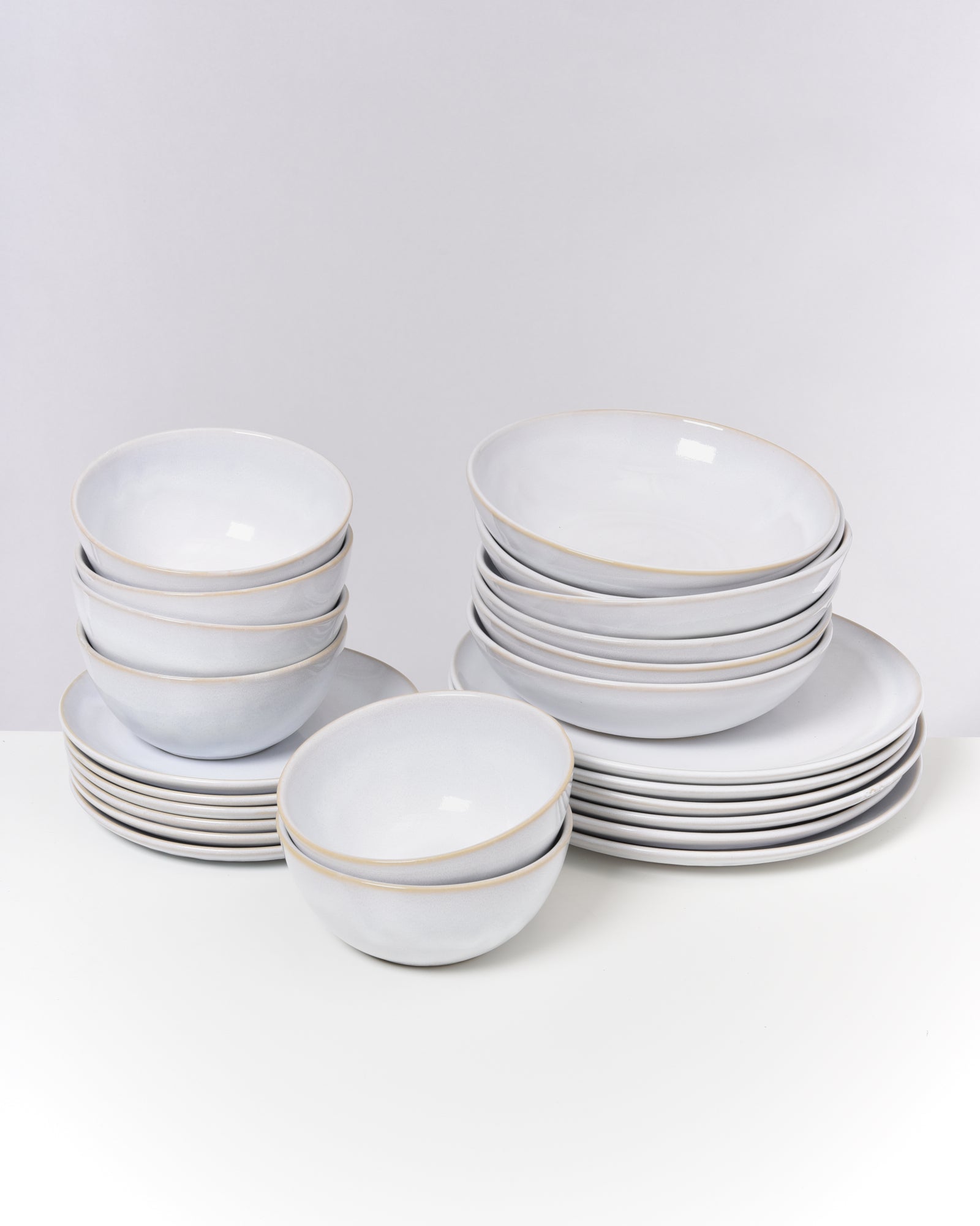 Ein Set aus weißen Tellern und Schalen gestapelt auf einem weißen Hintergrund.