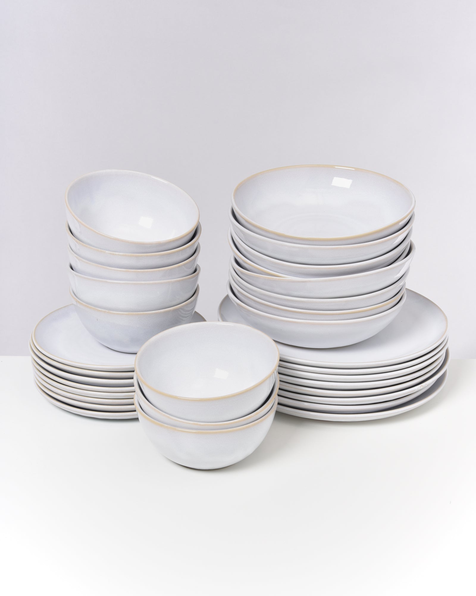 Ein Set aus gestapelten weißen Schalen und Tellern auf einem weißen Hintergrund.
