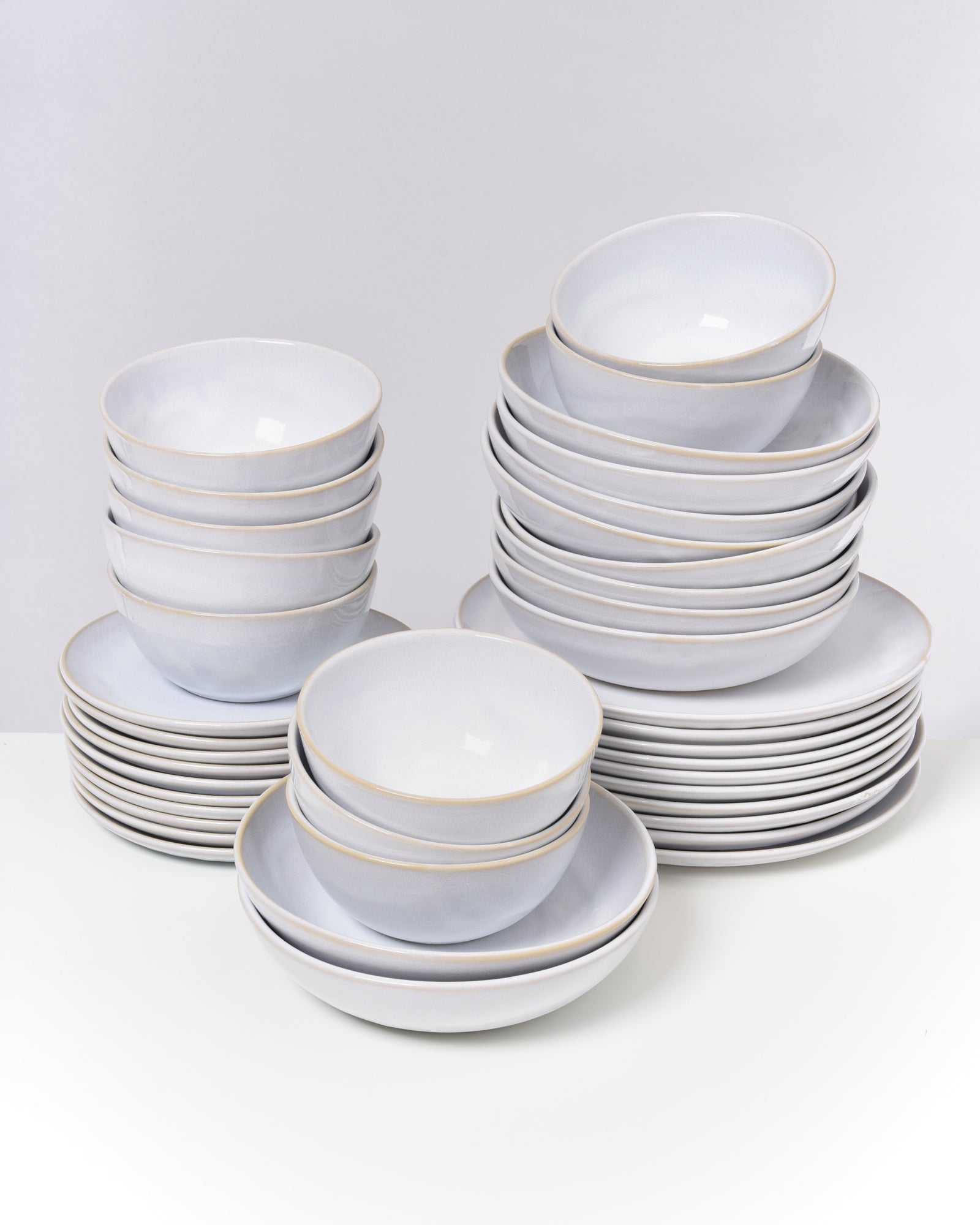 Mehrere gestapelte weiße Schüsseln und Teller auf einer weißen Oberfläche.