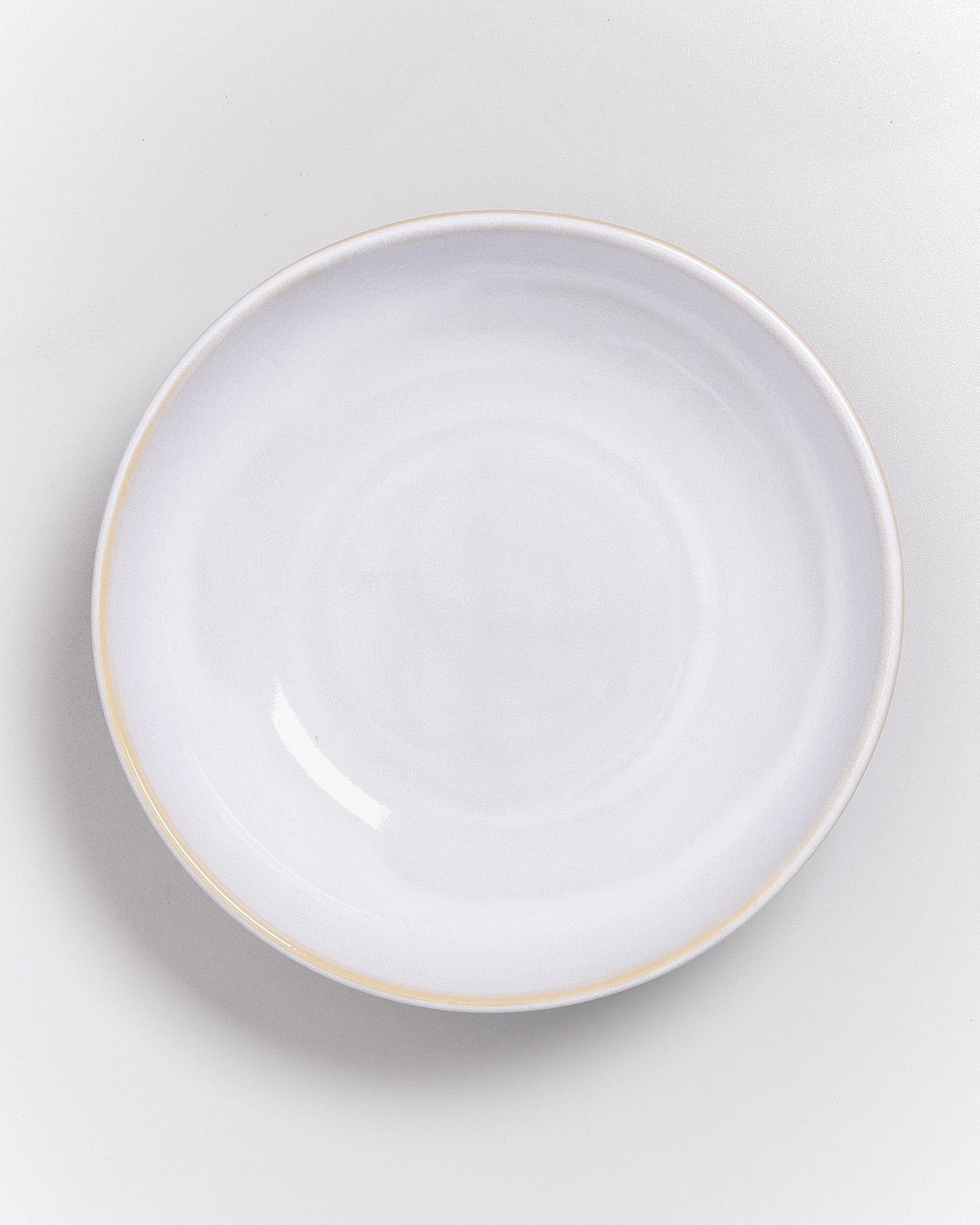 Weißer, runder Teller auf einer hellgrauen Oberfläche.