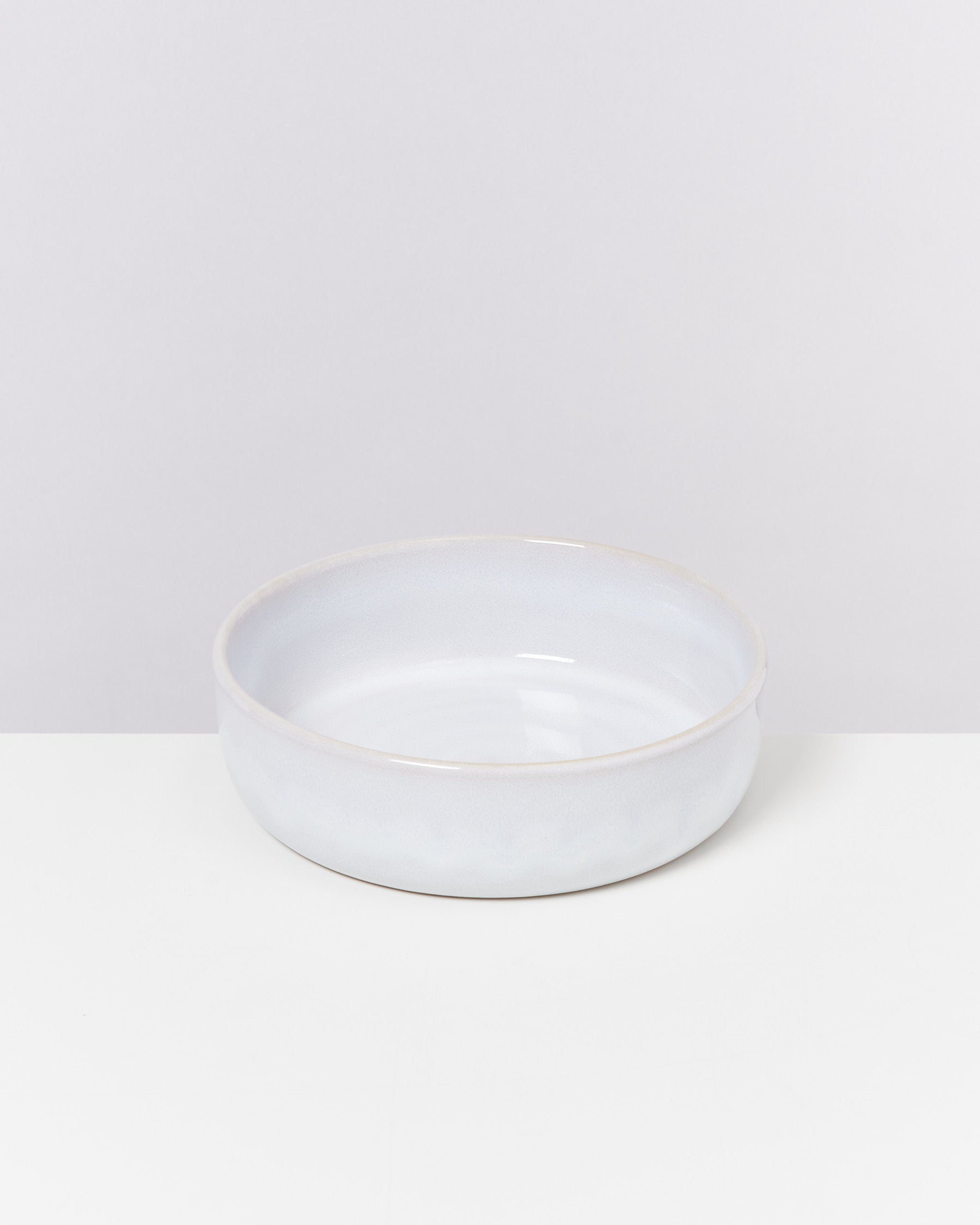 Weiße, runde Keramikschale auf einem weißen Hintergrund.