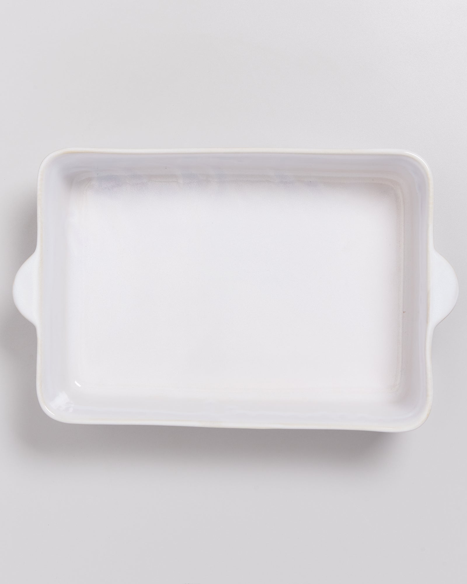 Weiße, rechteckige Auflaufform mit Henkeln auf hellem Hintergrund.