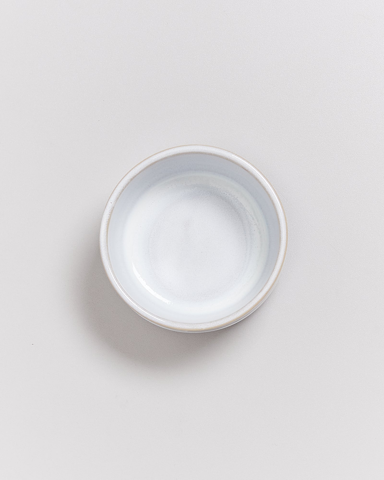 Eine leere, kleine, weiße Schale auf einem hellen Hintergrund.