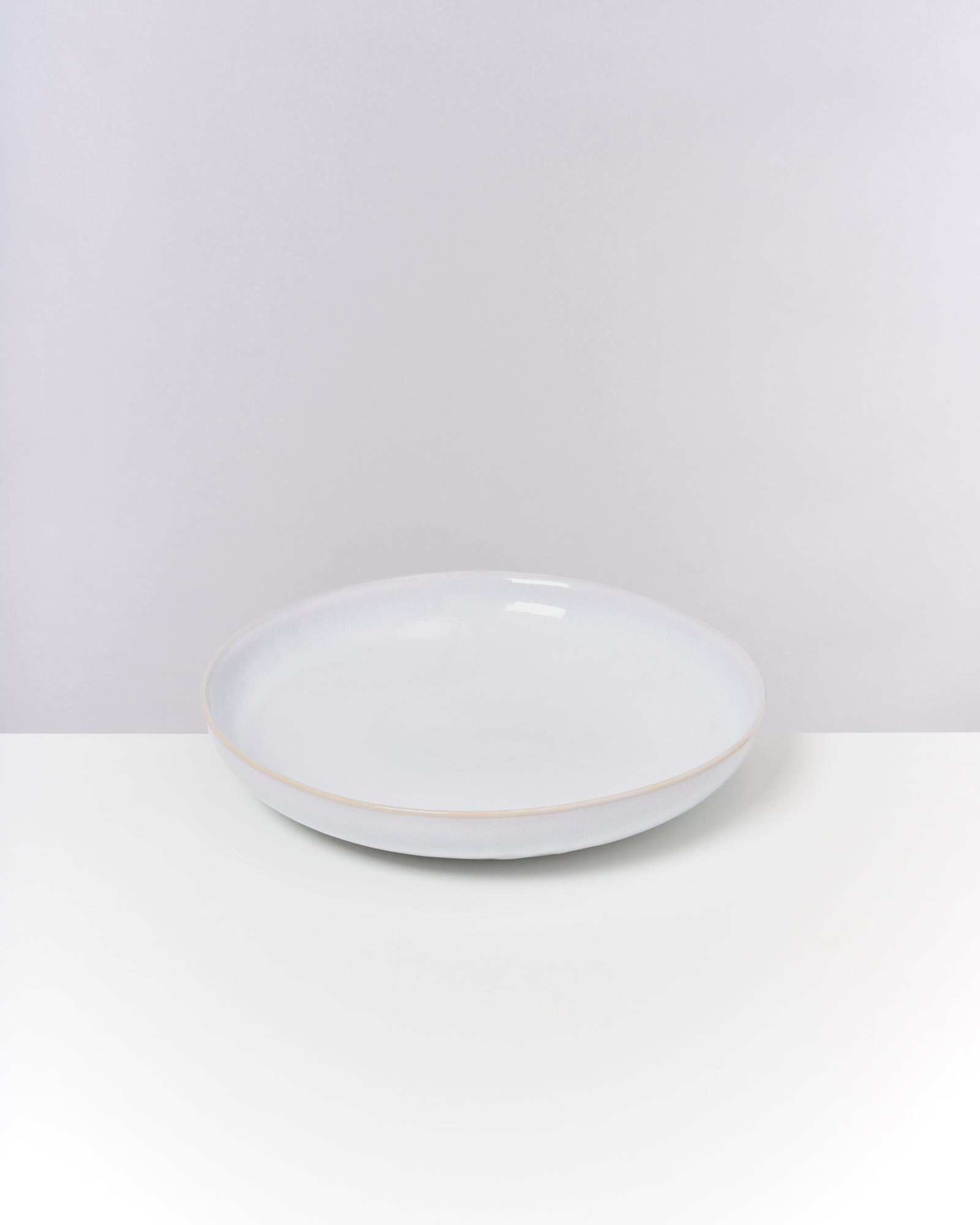 Weiße Keramikschale auf weißem Hintergrund und Tisch.