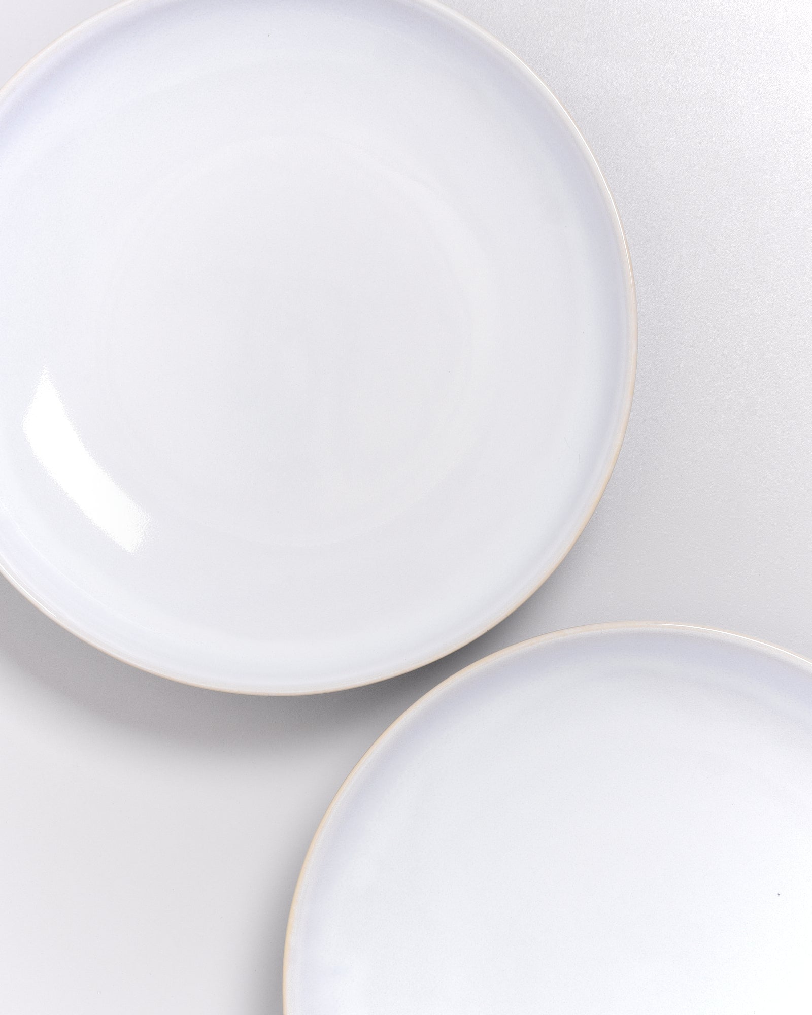 Zwei weiße, runde Teller auf einer weißen Oberfläche.