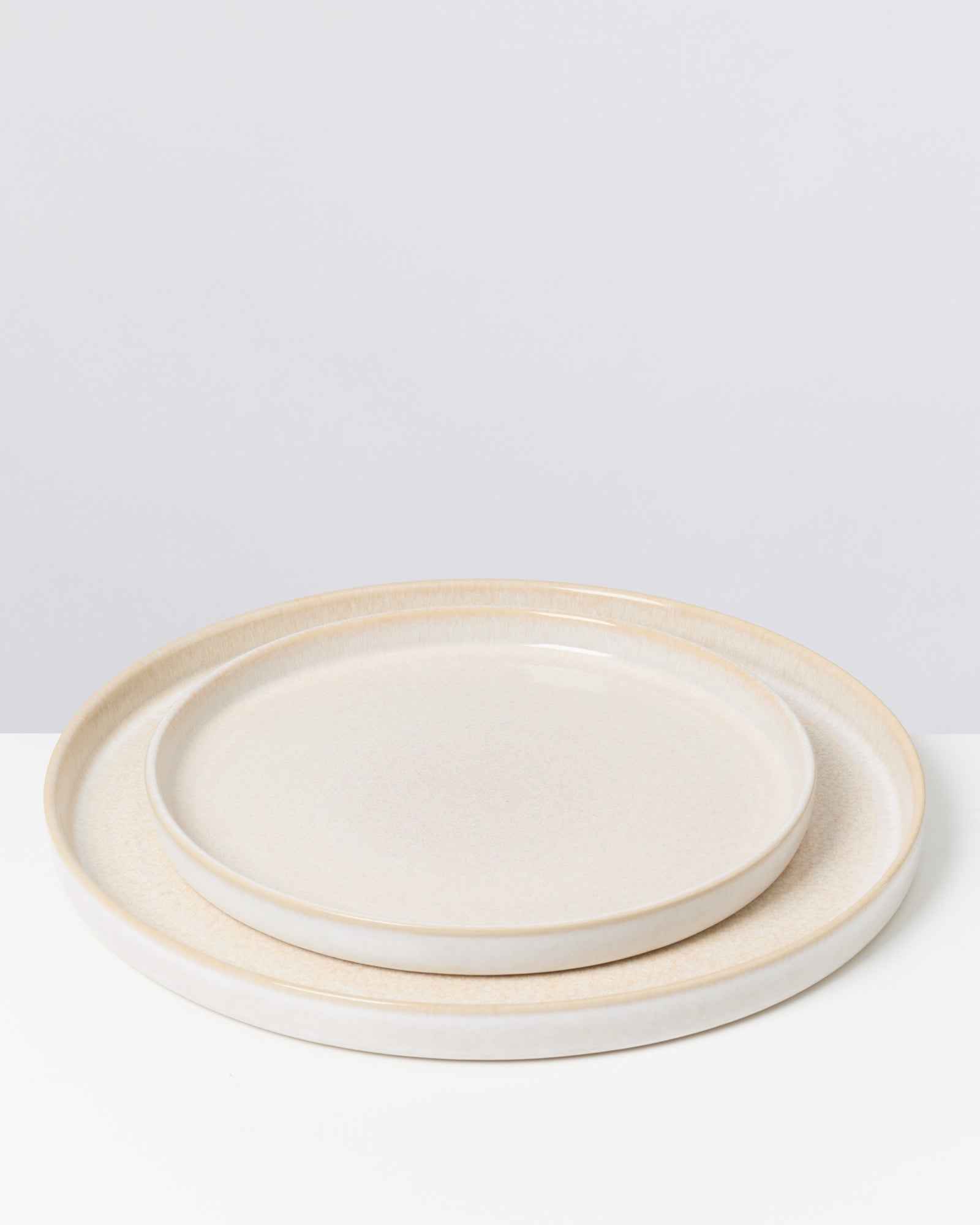 Zwei beigefarbene, ineinander gestapelte Teller auf einem weißen Hintergrund.