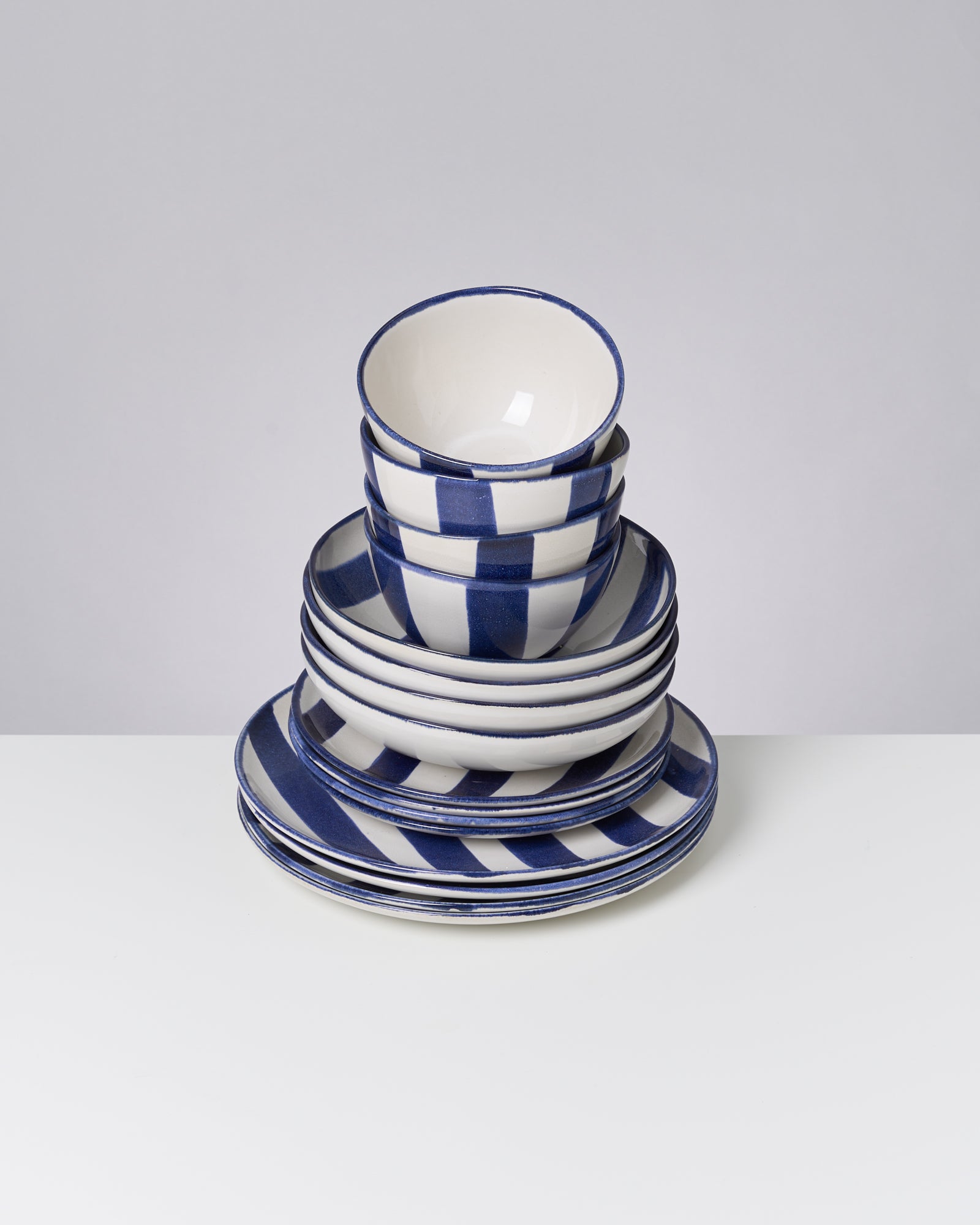 Gestapelte Teller und Schalen mit blau-weißen Streifen auf einem Tisch.