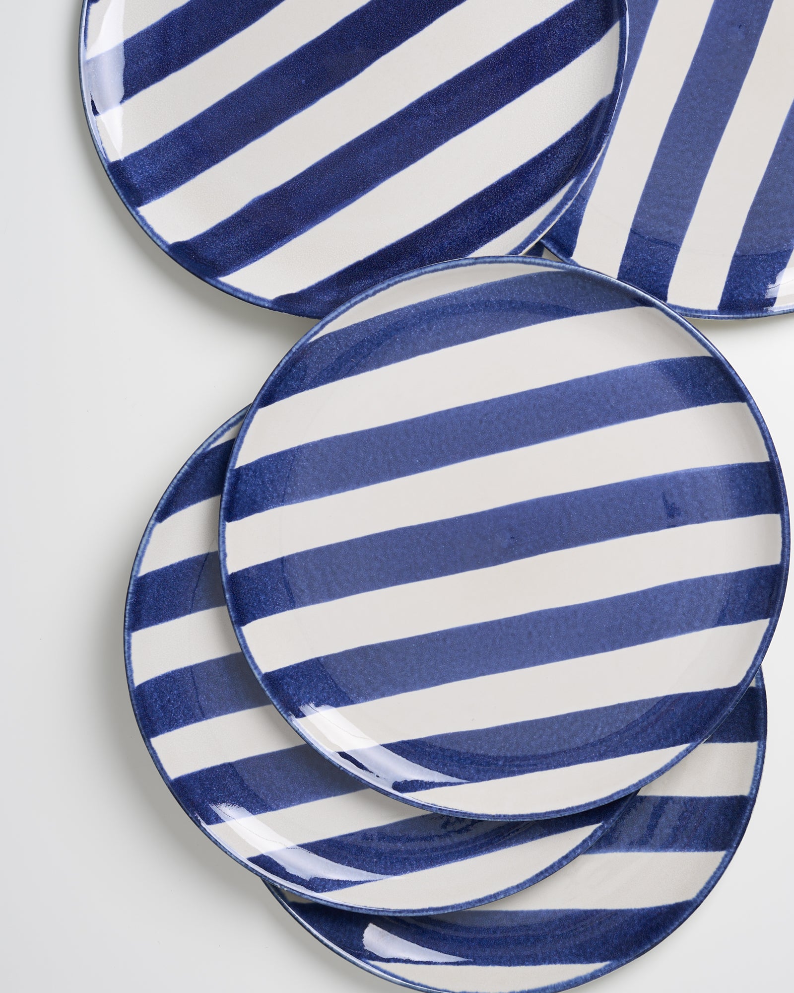 Fünf Teller mit blauen und weißen Streifen liegen auf einem weißen Hintergrund.