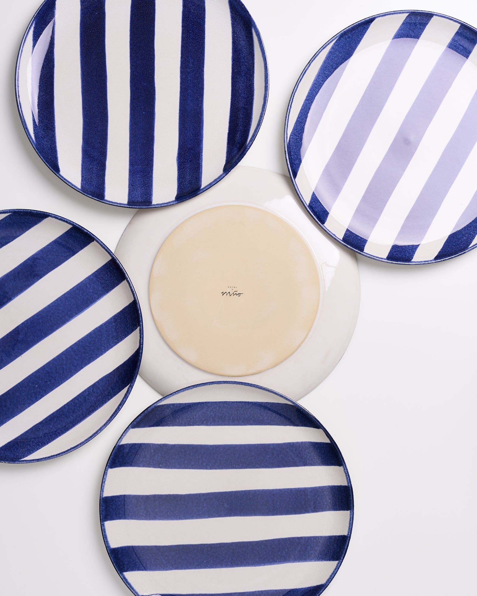 Fünf Teller mit blauen und weißen Streifenmustern in einer kreisförmigen Anordnung.