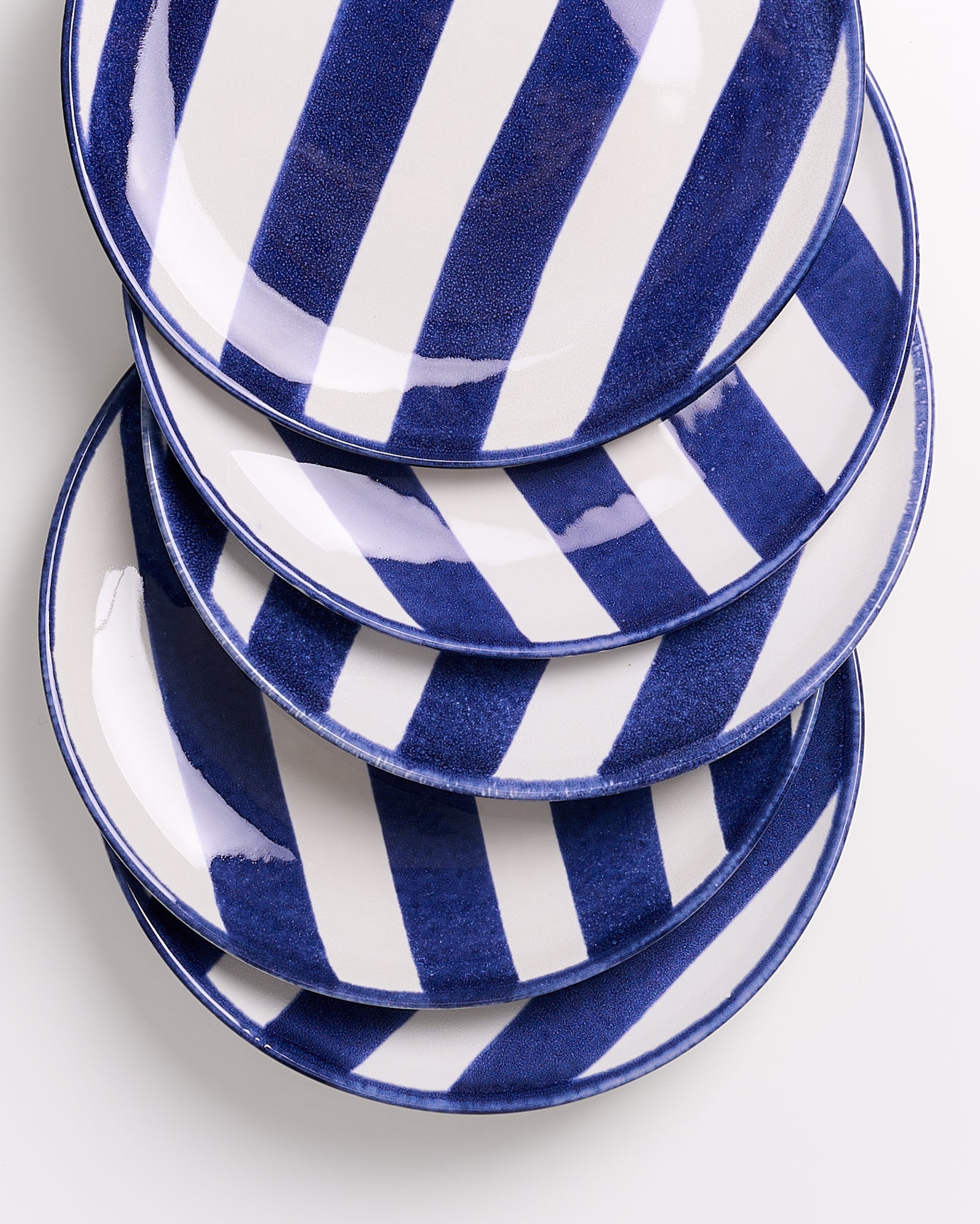 Ein Stapel von fünf Tellern mit blau-weißen Streifen auf einem weißen Hintergrund.