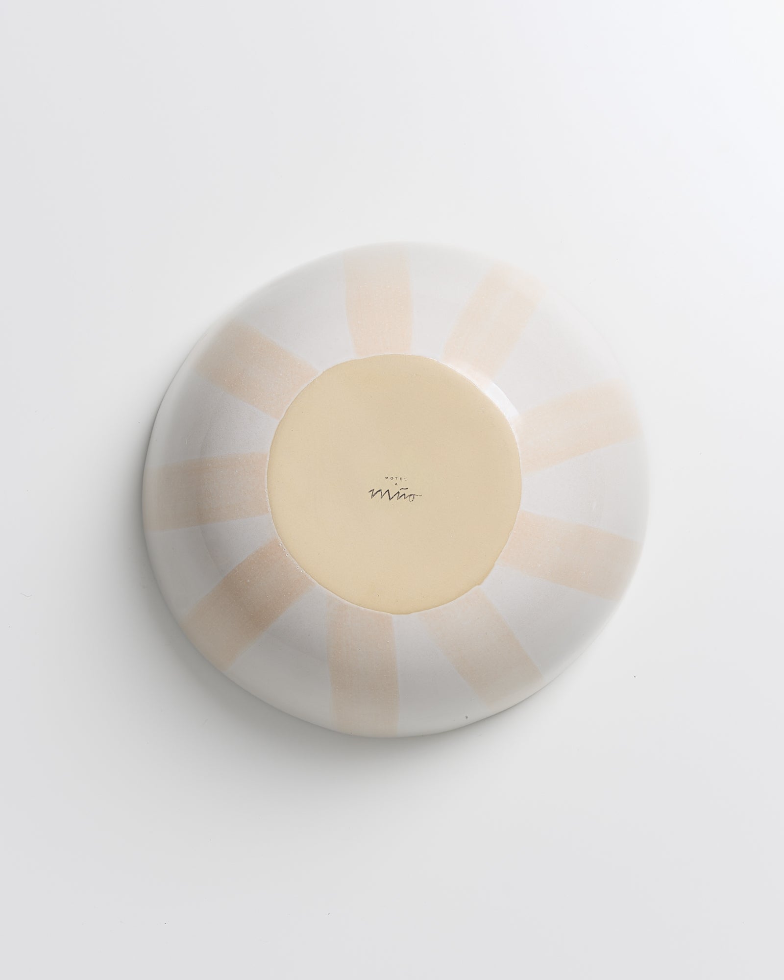 Runde Keramikschale mit hellen, strahlenförmigen Mustern auf der Unterseite, auf einem weißen Hintergrund.