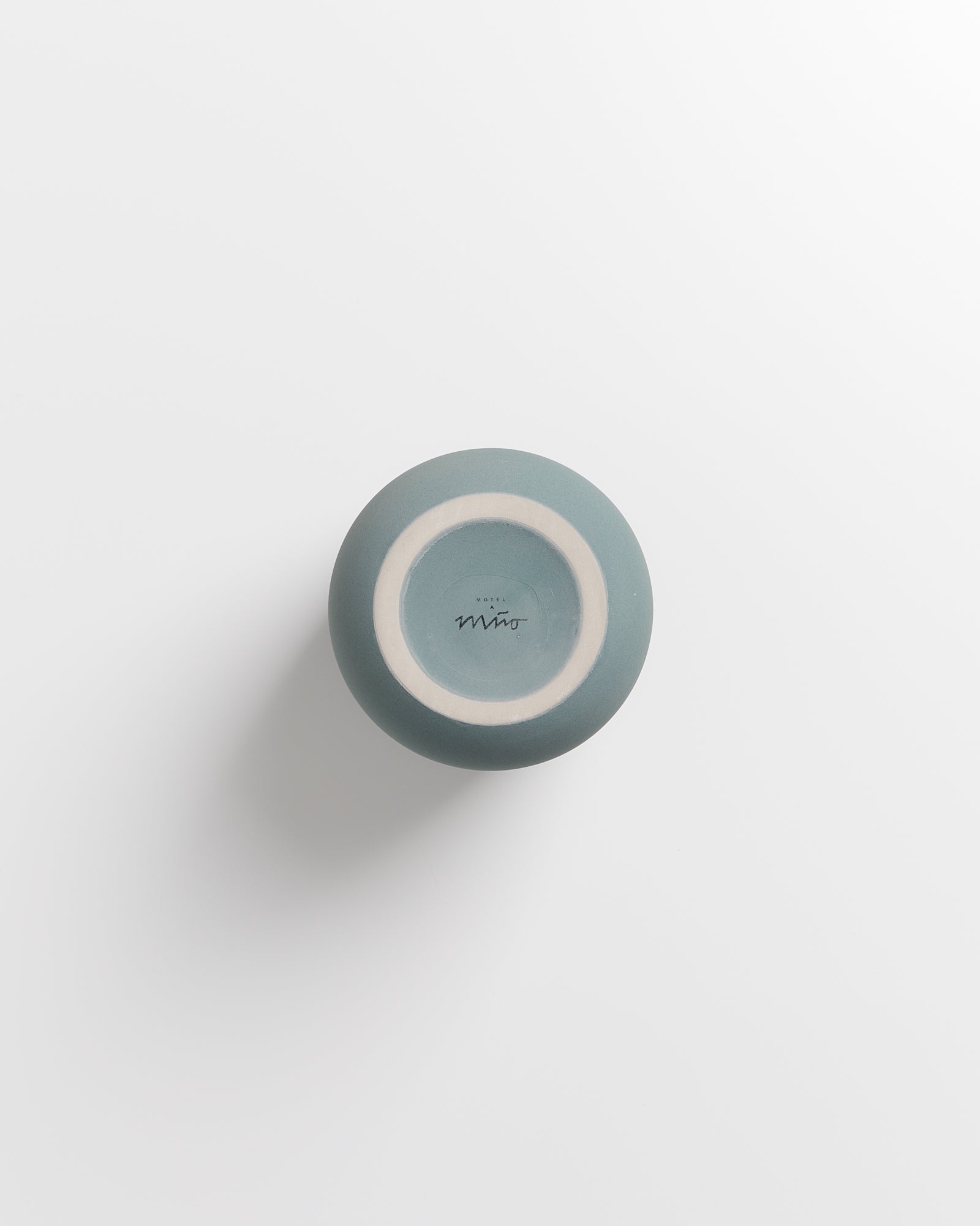 Blaue Keramikschale mit Logo auf der Unterseite, auf einem weißen Hintergrund fotografiert.