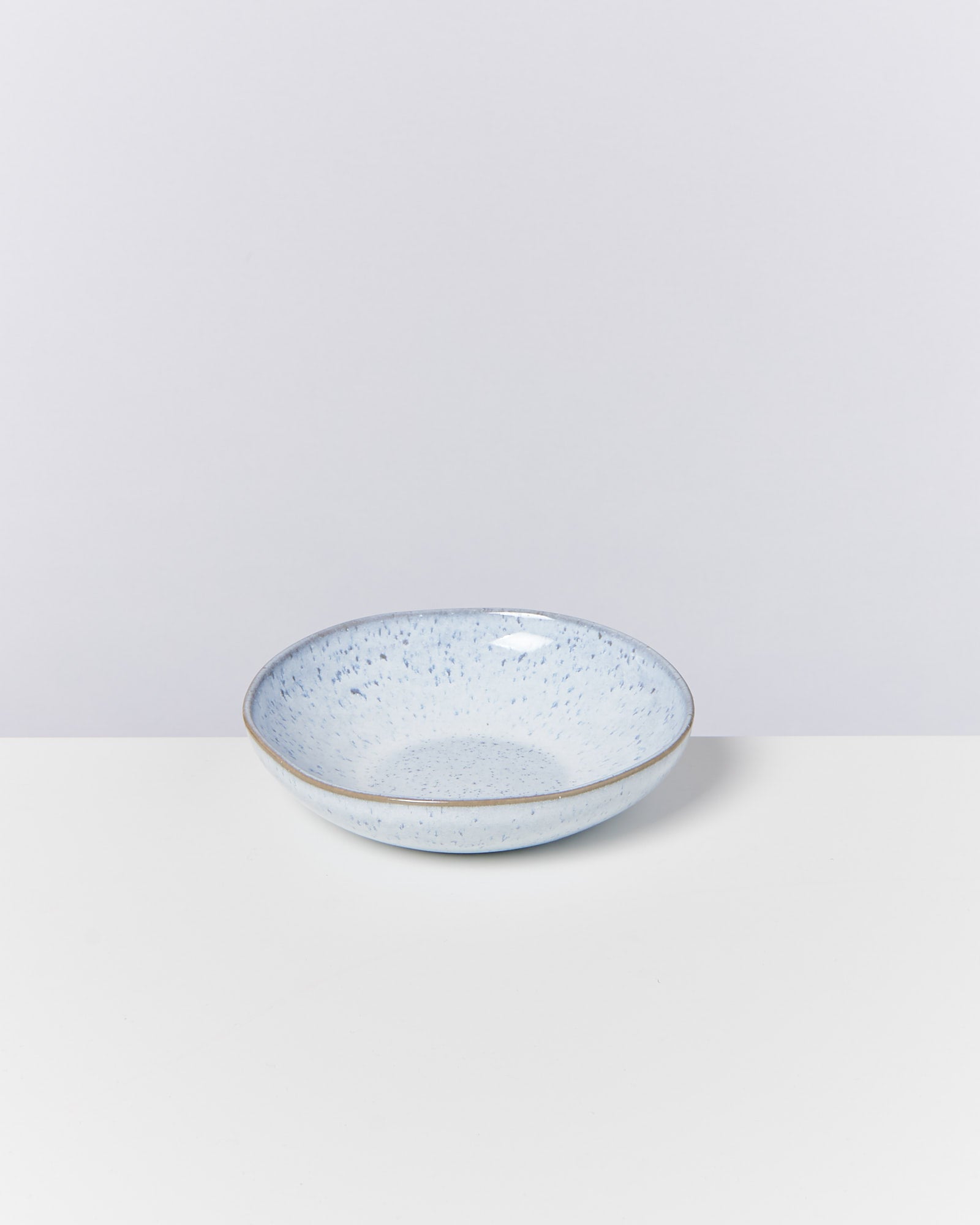 Blaue, gefleckte Keramikschale auf weißem Hintergrund.