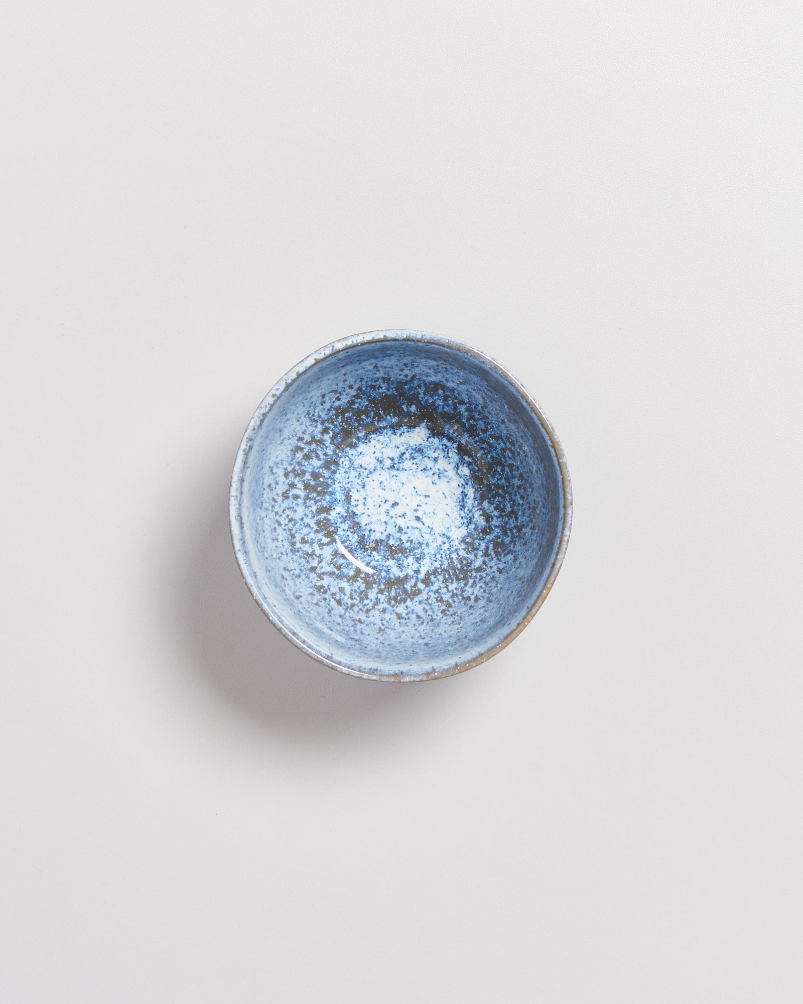 Eine blaue, gesprenkelte Keramikschale auf einem hellgrauen Hintergrund.