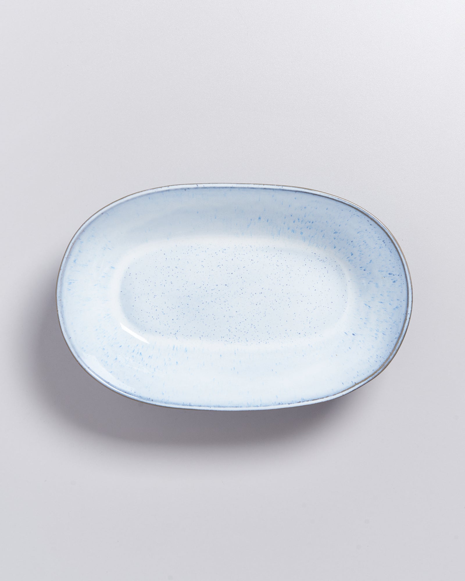 Hellblauer, länglicher Keramikteller mit Sprenkeln auf hellem Hintergrund.