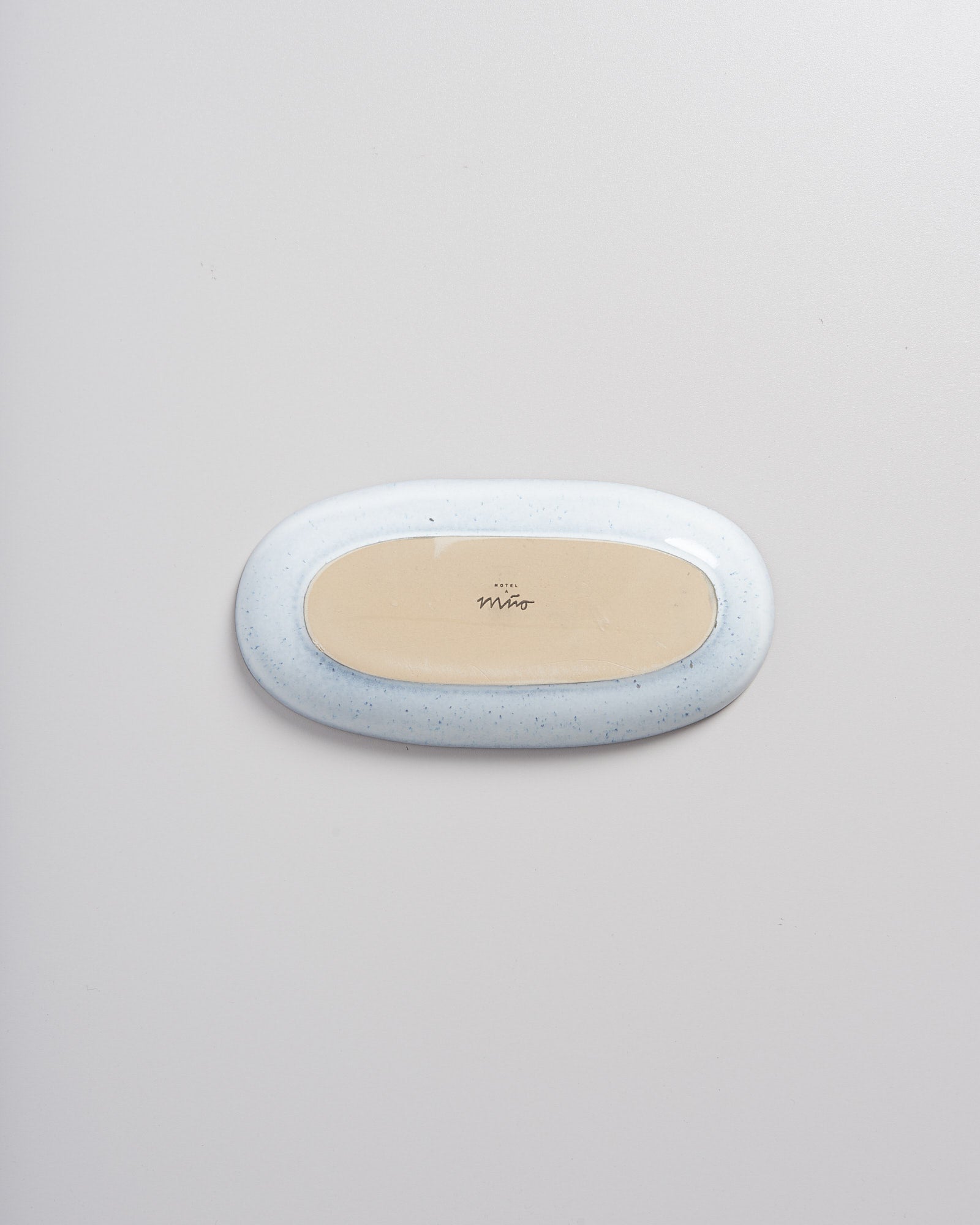 Ovale, hellblaue Seifenschale mit beiger Innenseite auf weißem Hintergrund.