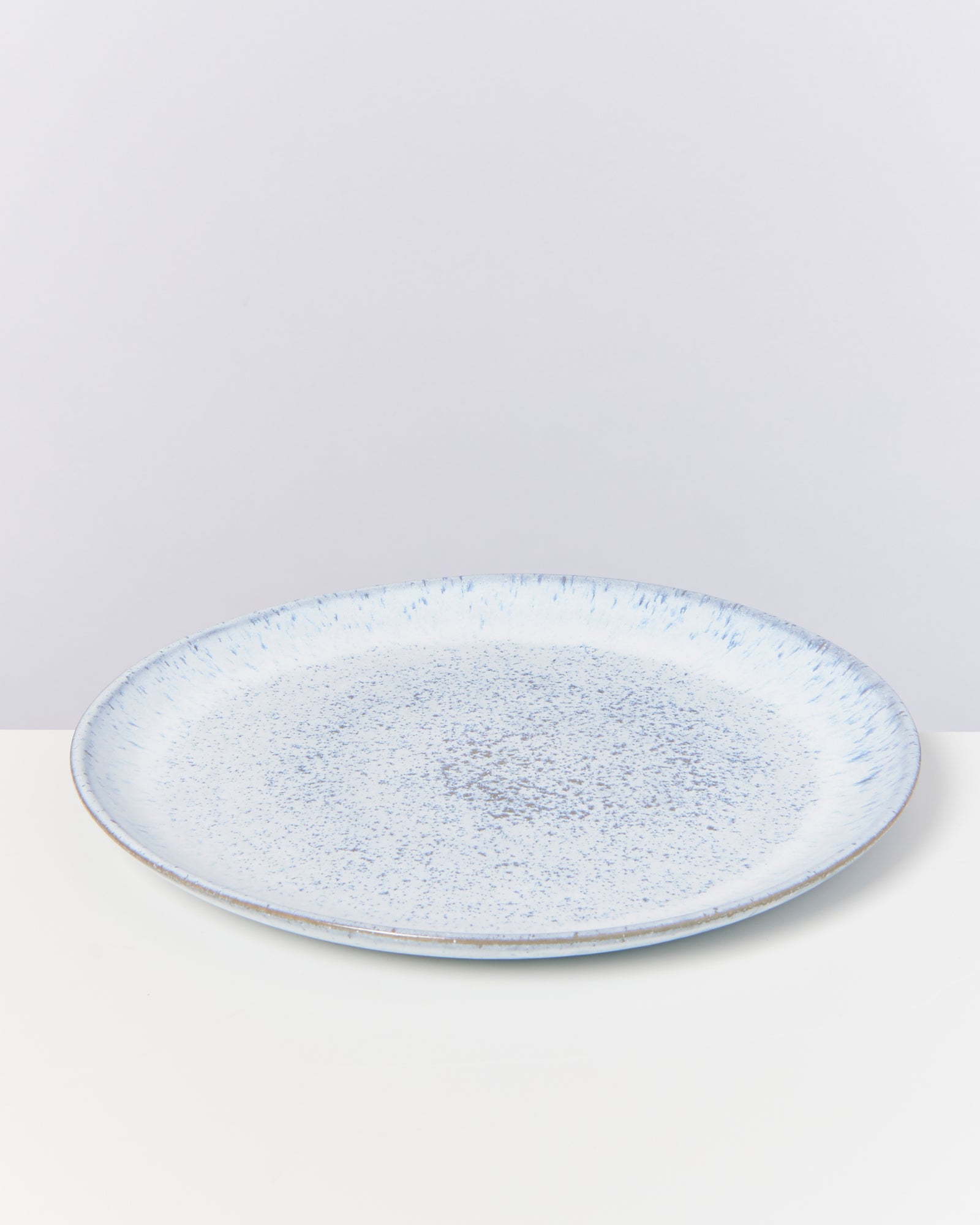 Blauer Keramikteller mit gesprenkeltem Muster auf weißem Hintergrund.