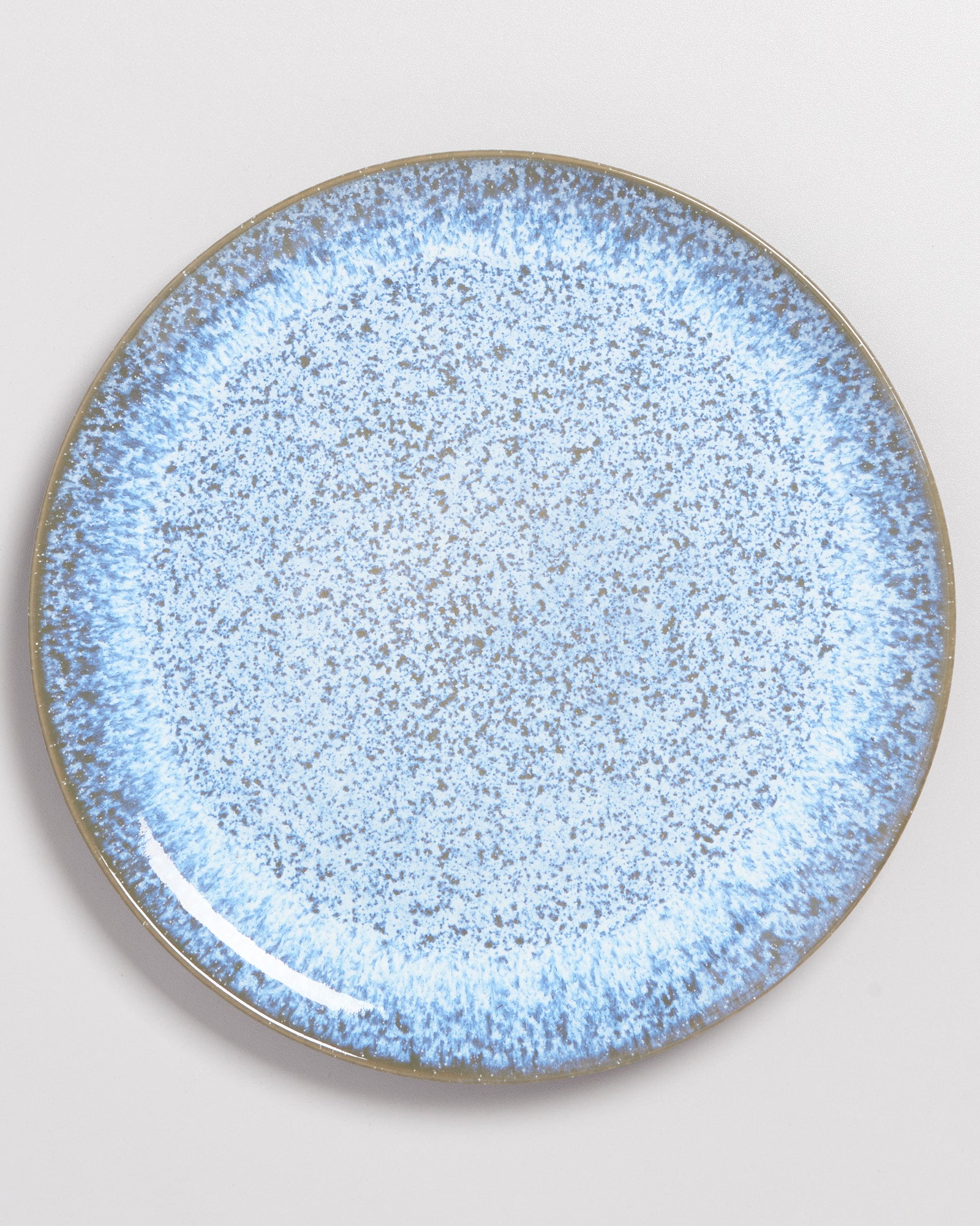 Runder Teller mit blaugrauem Sprenkelmuster auf weißem Hintergrund.