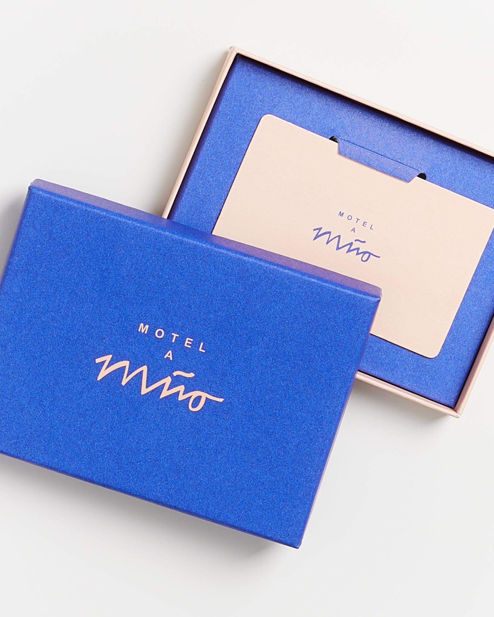 Blaue Schachtel mit dem Aufdruck "Motel a Miio" enthält eine Geschenk- oder Grußkarte in Blau und Rosa.