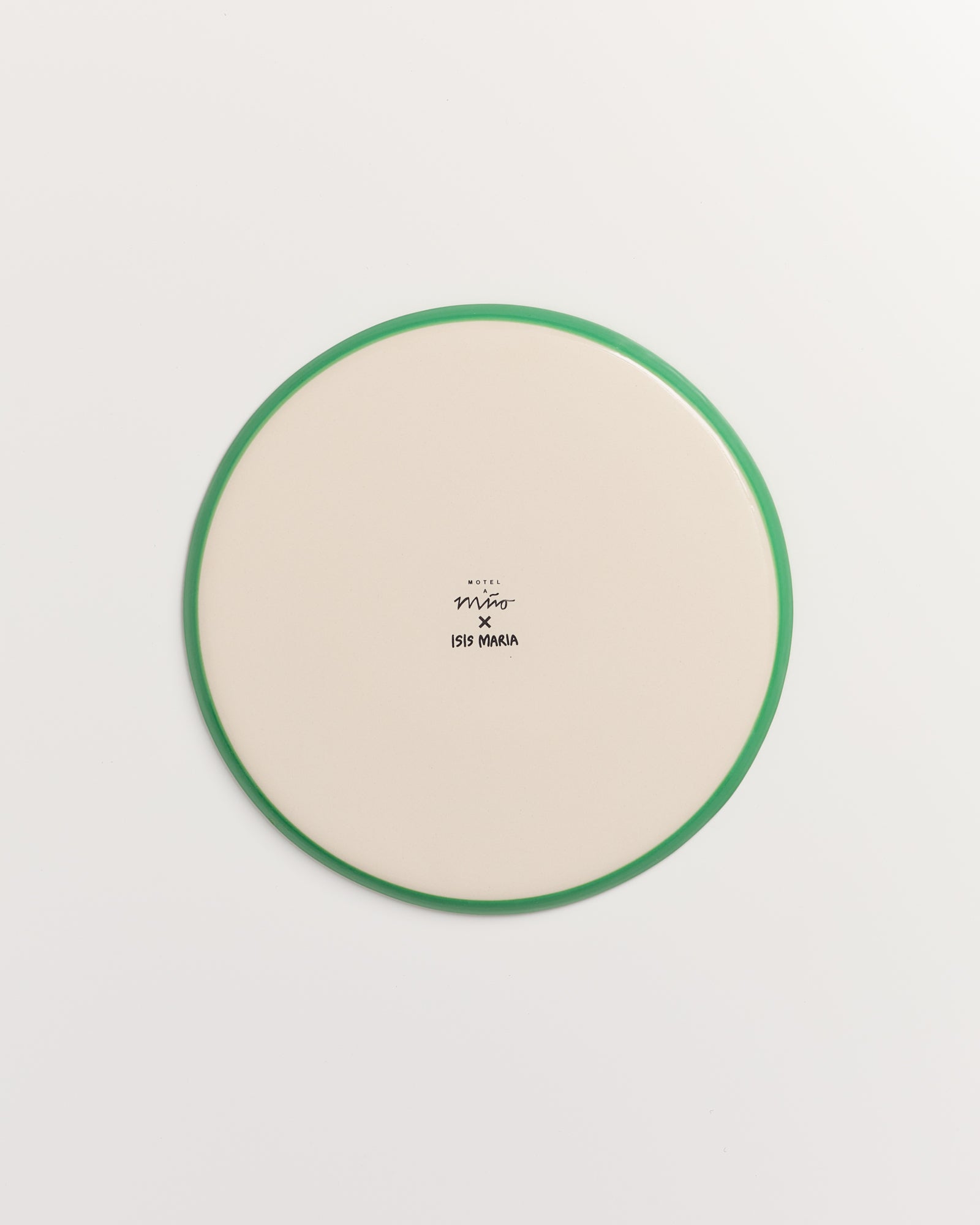 Runder Teller mit grünem Rand und Text "Motel a Miio x ISIS MARIA" auf cremefarbenem Hintergrund.