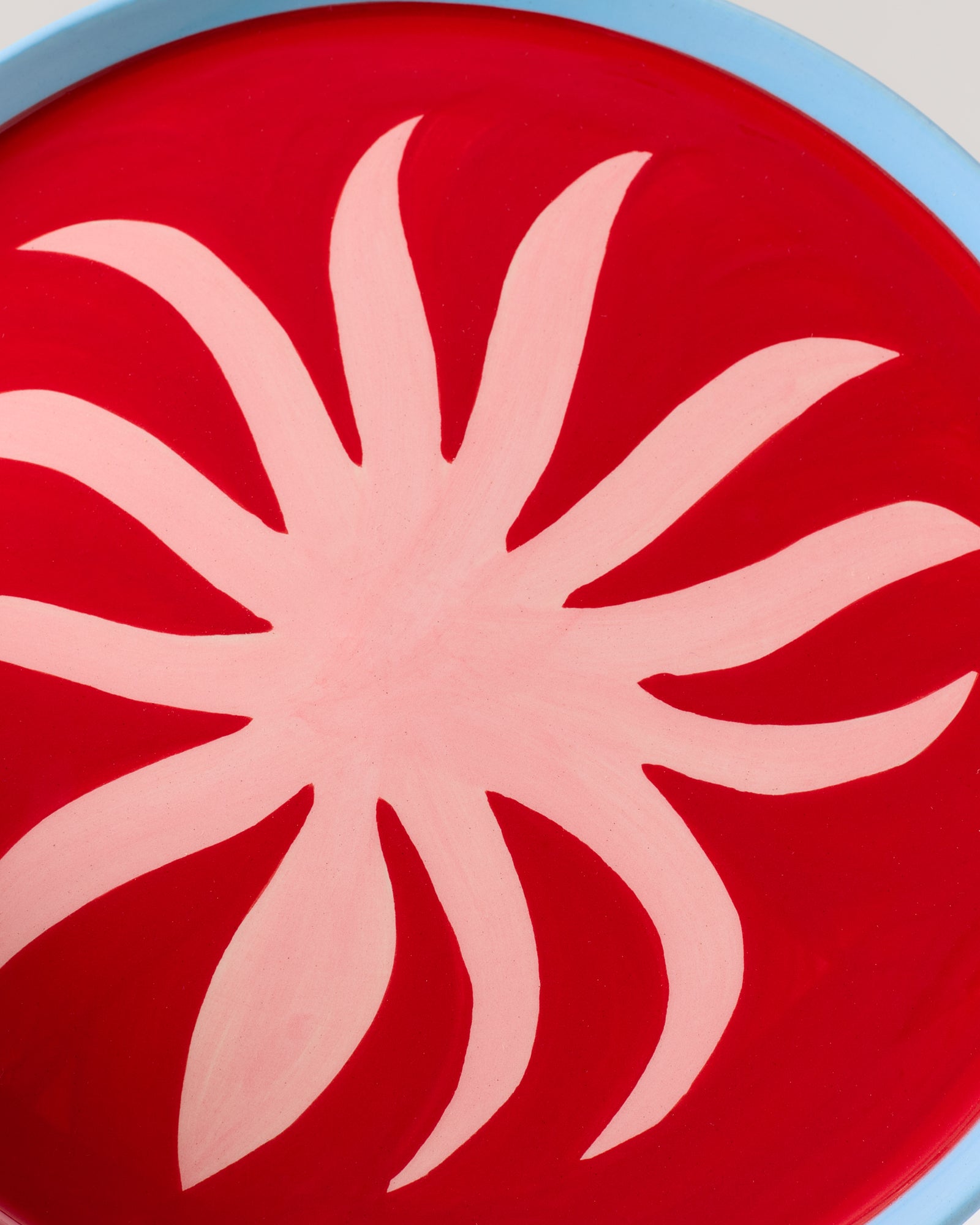 Abstraktes Kunstwerk mit einer roten Basis und einem blassrosa, blütenartigen Muster in der Mitte.