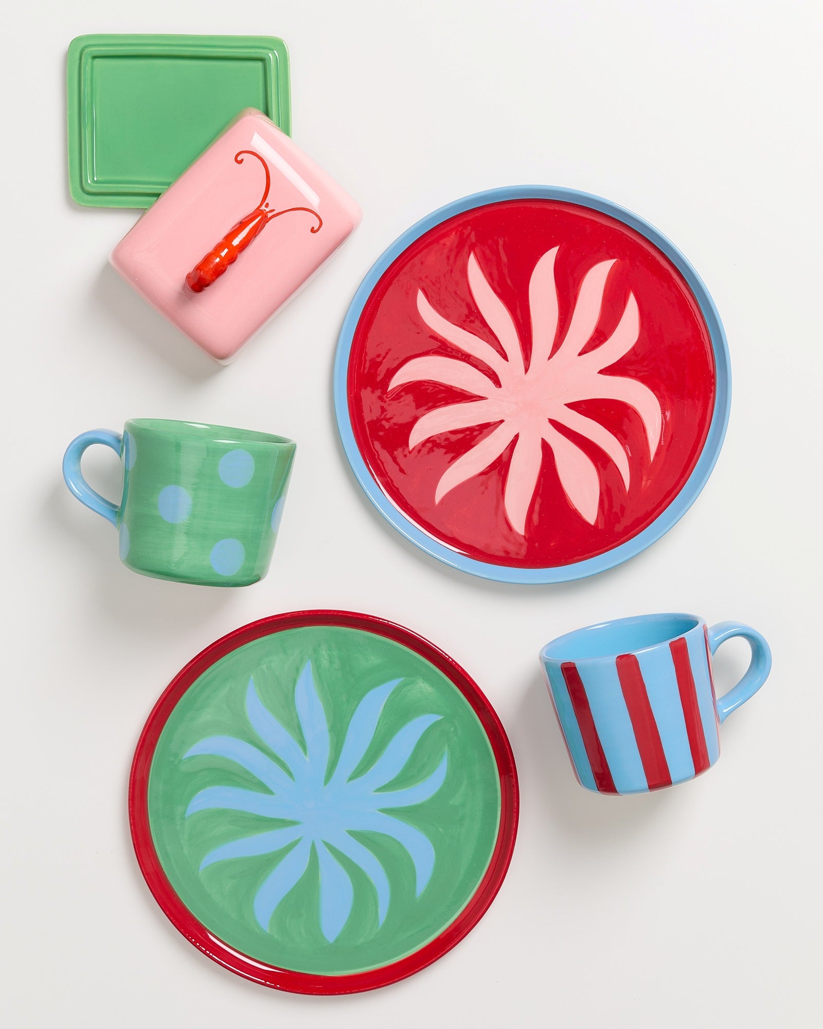 Buntes Keramikgeschirr, einschließlich zweier gemusterter Teller und Tassen, sowie eine Schale mit einem Hummerdeckel.