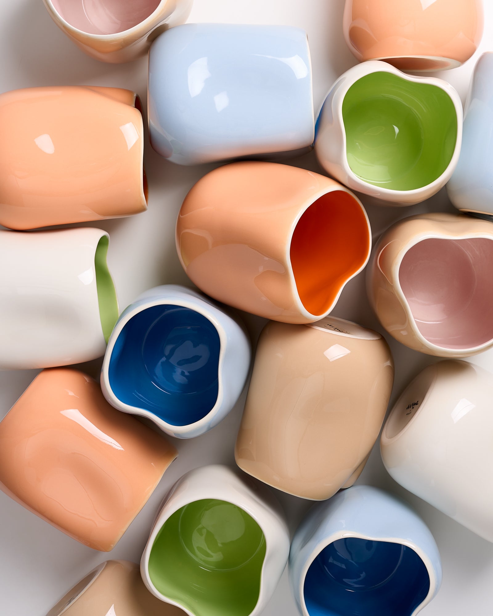 Verschiedene bunte, glatte Keramikgefäße mit unregelmäßigen Formen und gemusterten Innenfarben.