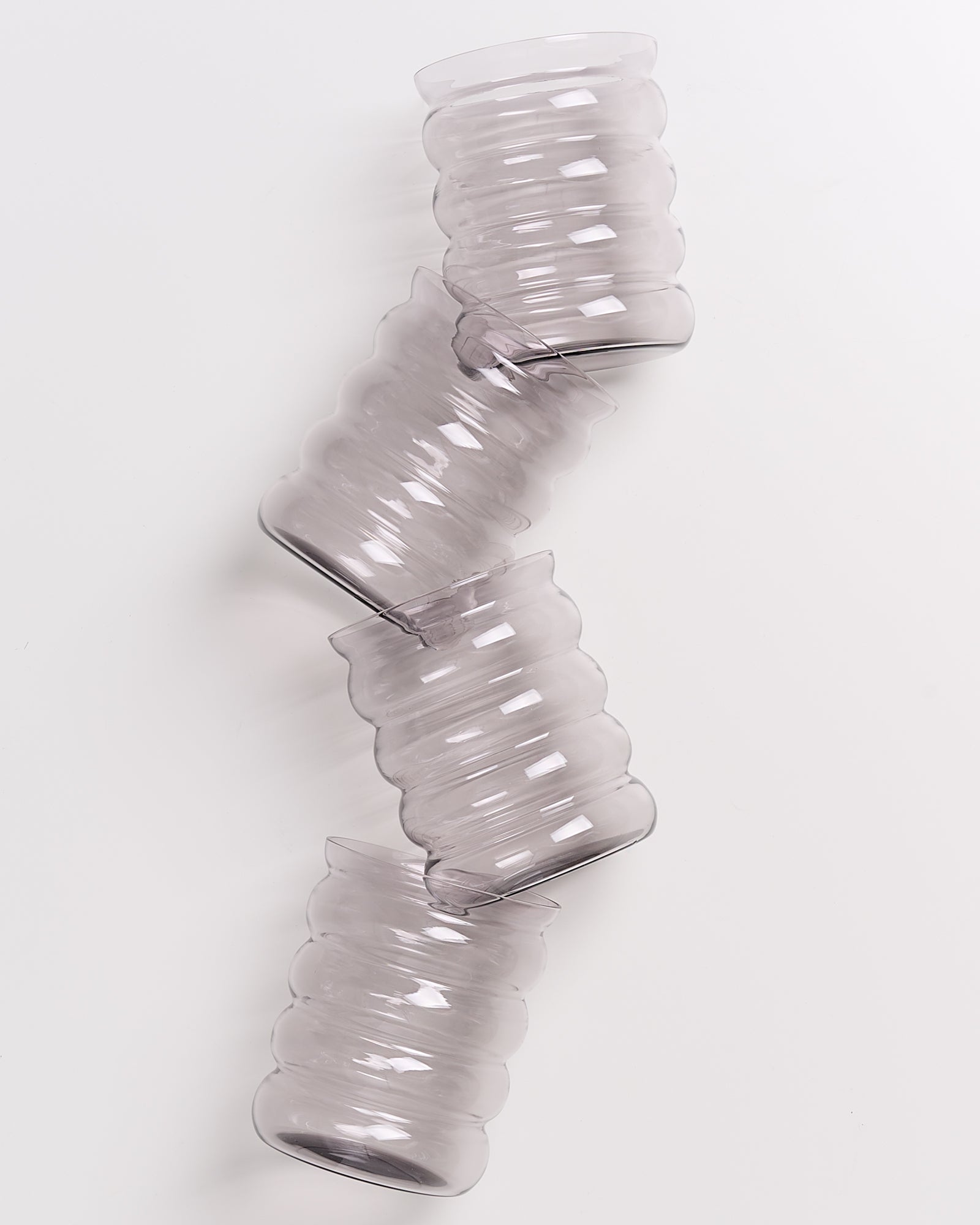 Drei übereinander gestapelte, geriffelte Glasvasen auf einem weißen Hintergrund.