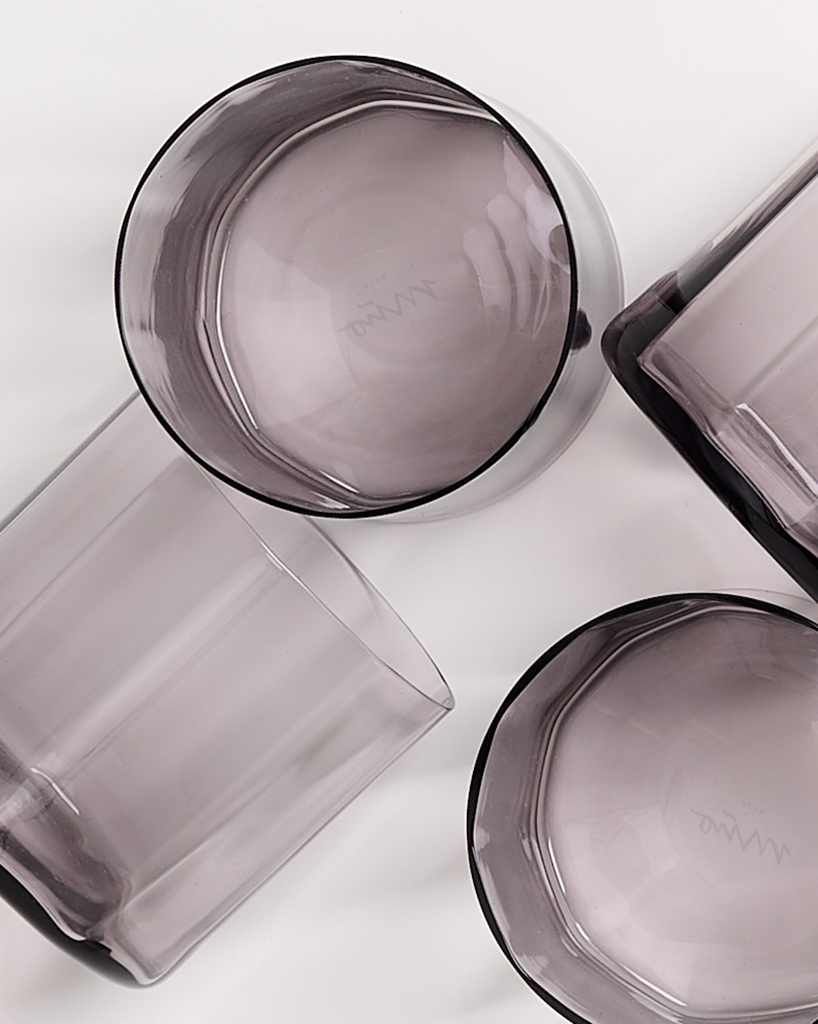 Drei graue, durchsichtige Gläser liegen auf einer weißen Oberfläche.