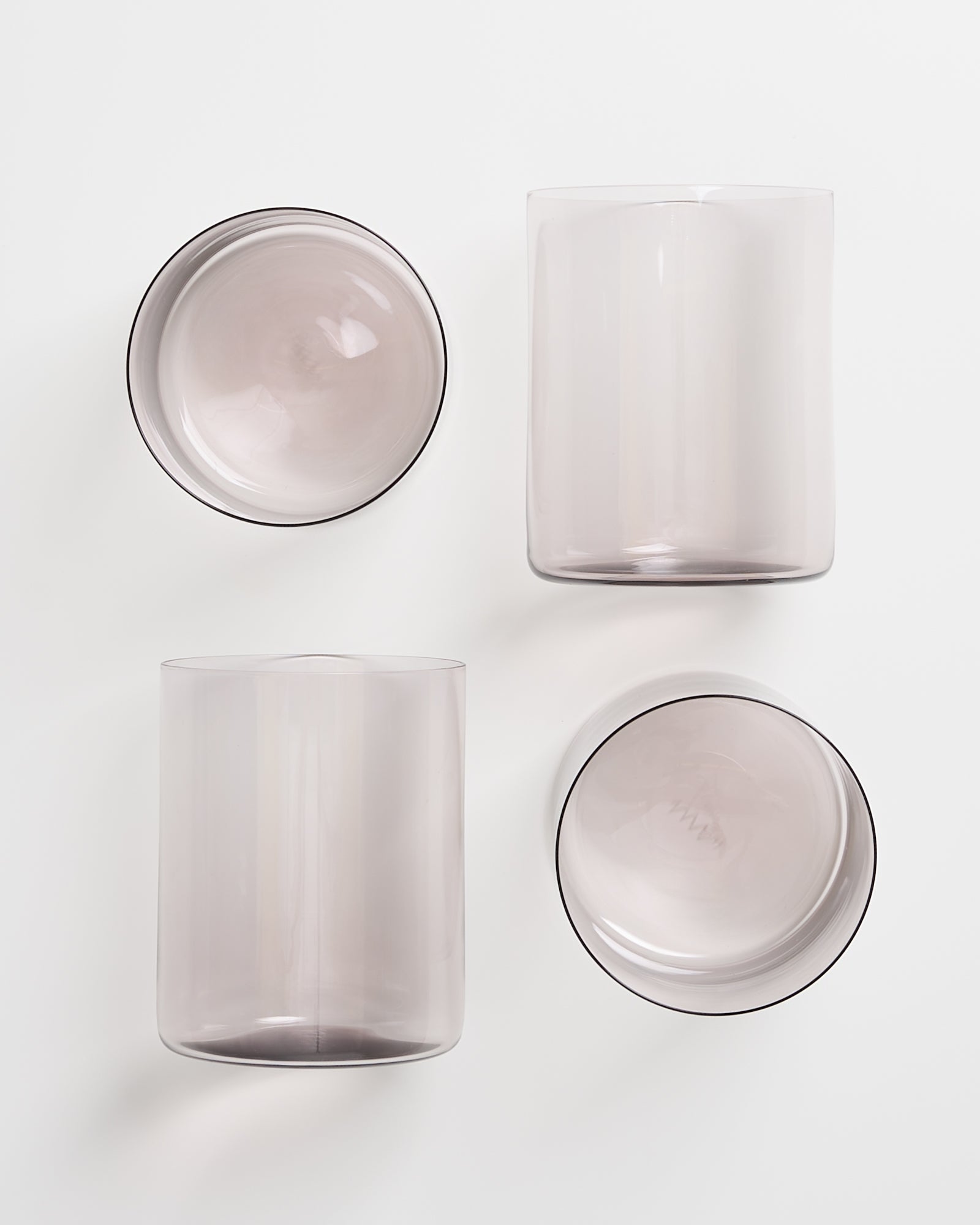 Vier durchsichtige Gläser in verschiedenen Formen auf weißem Hintergrund.