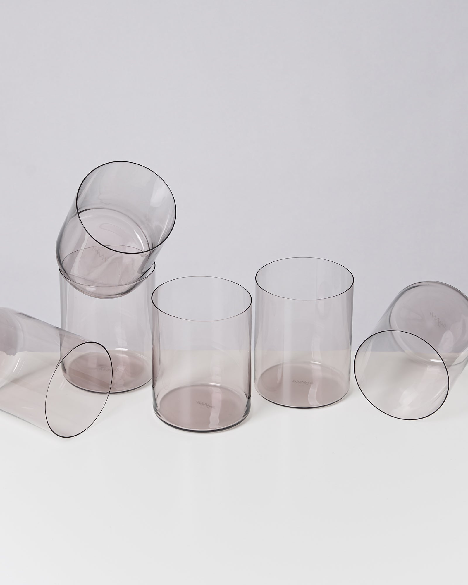 Mehrere leere, transparente Gläser in verschiedenen Positionen auf einem weißen Hintergrund.