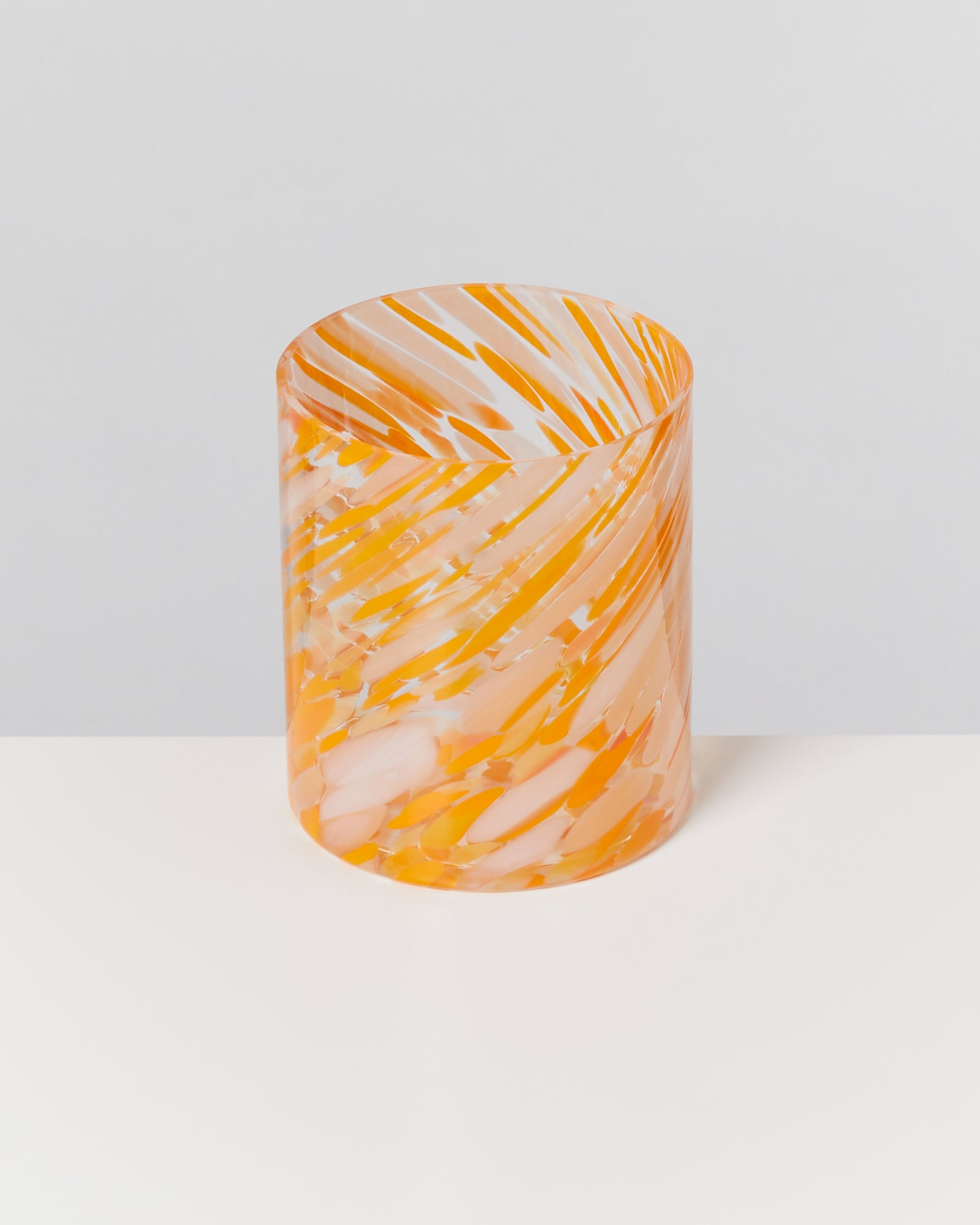 Transparenter Zylinder mit orange-weißen Wirbelmustern auf einem weißen Hintergrund.