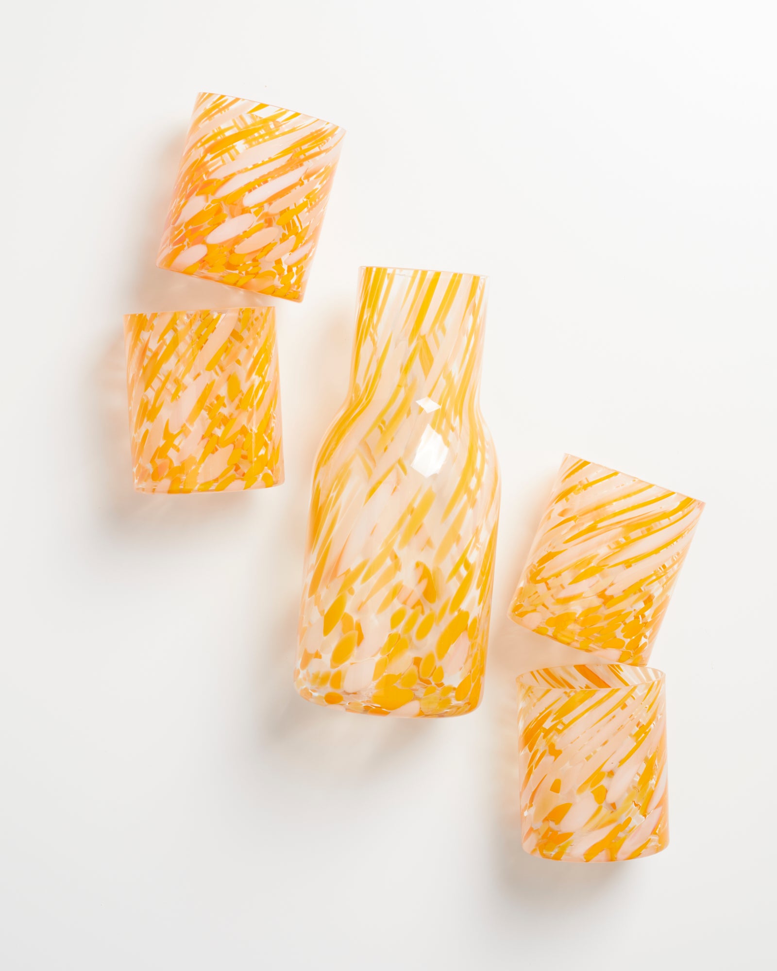 Fünf Gläser mit orangefarbenem, wirbelndem Muster auf weißem Hintergrund, eines davon ist größer und gebogen.