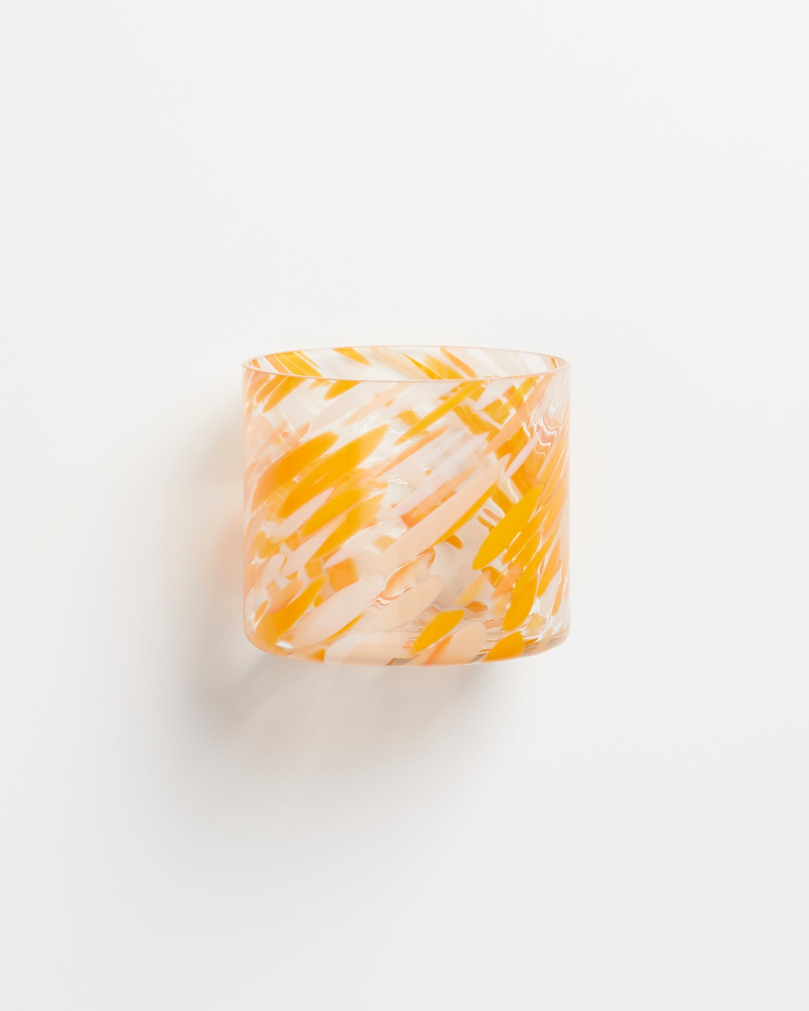 Bunt gemustertes Glas mit gelben und weißen Mustern auf weißem Hintergrund.