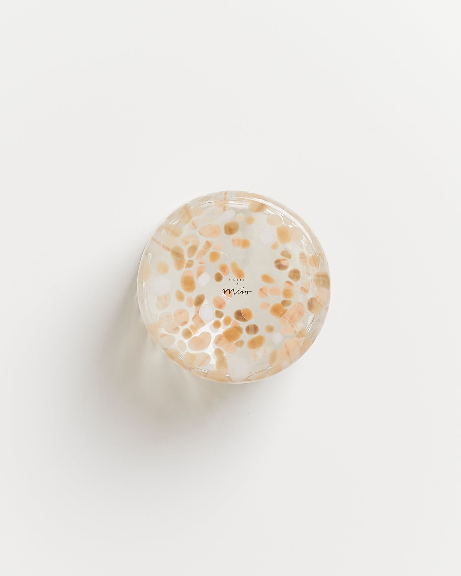 Runder, durchsichtiger Aschenbecher mit orange-weißen Mustern auf einer weißen Oberfläche.