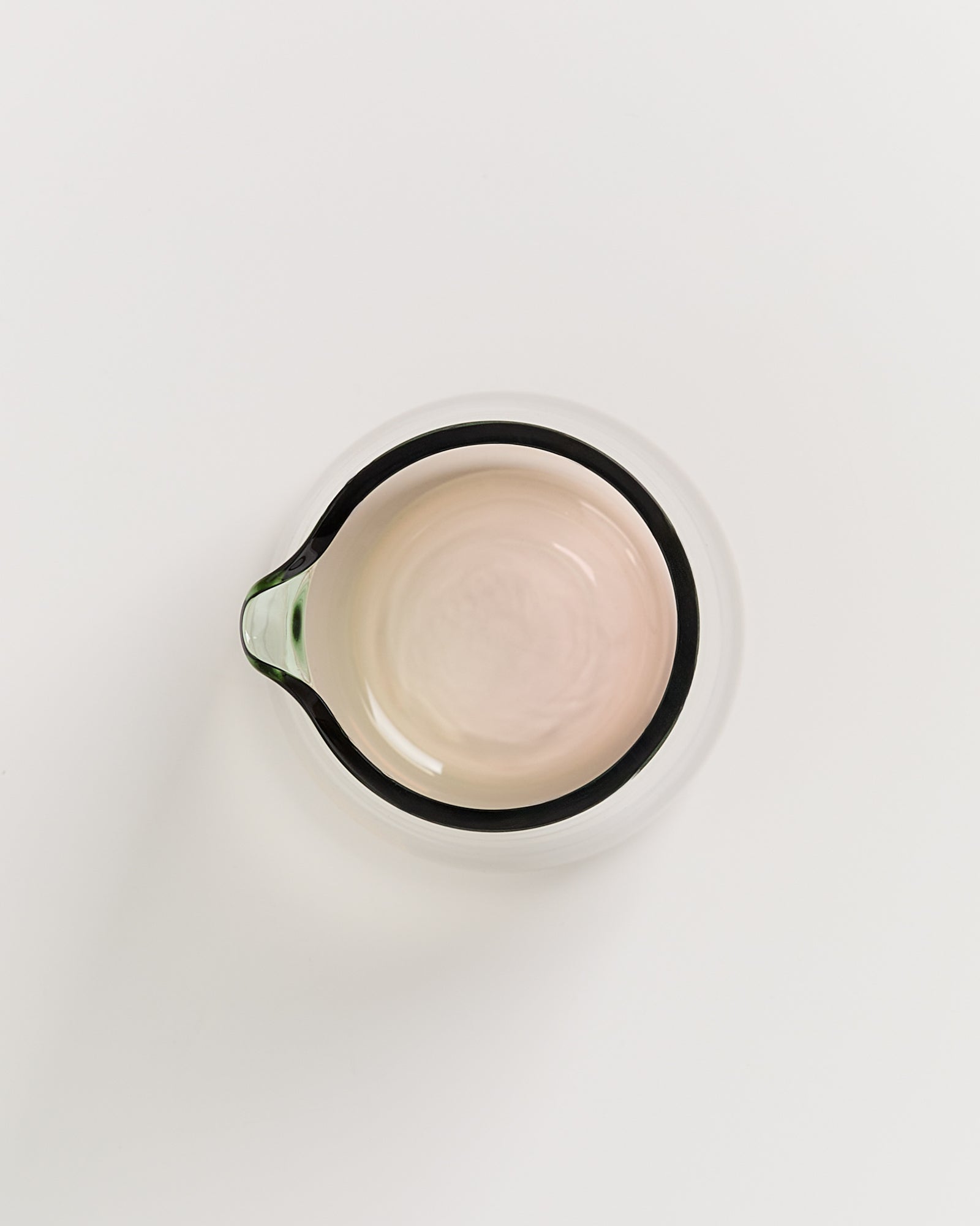 Ansicht von oben auf eine leere, transparente Glasschüssel mit Tülle auf weißem Hintergrund.