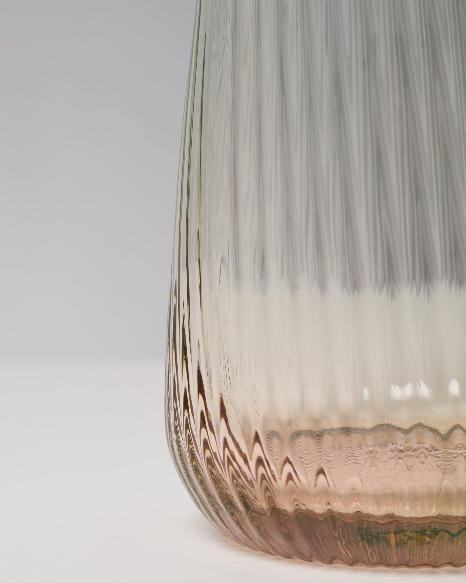 Nahaufnahme einer strukturierten Glasvase mit Farbverlauf von Braun zu Transparent auf weißem Hintergrund.