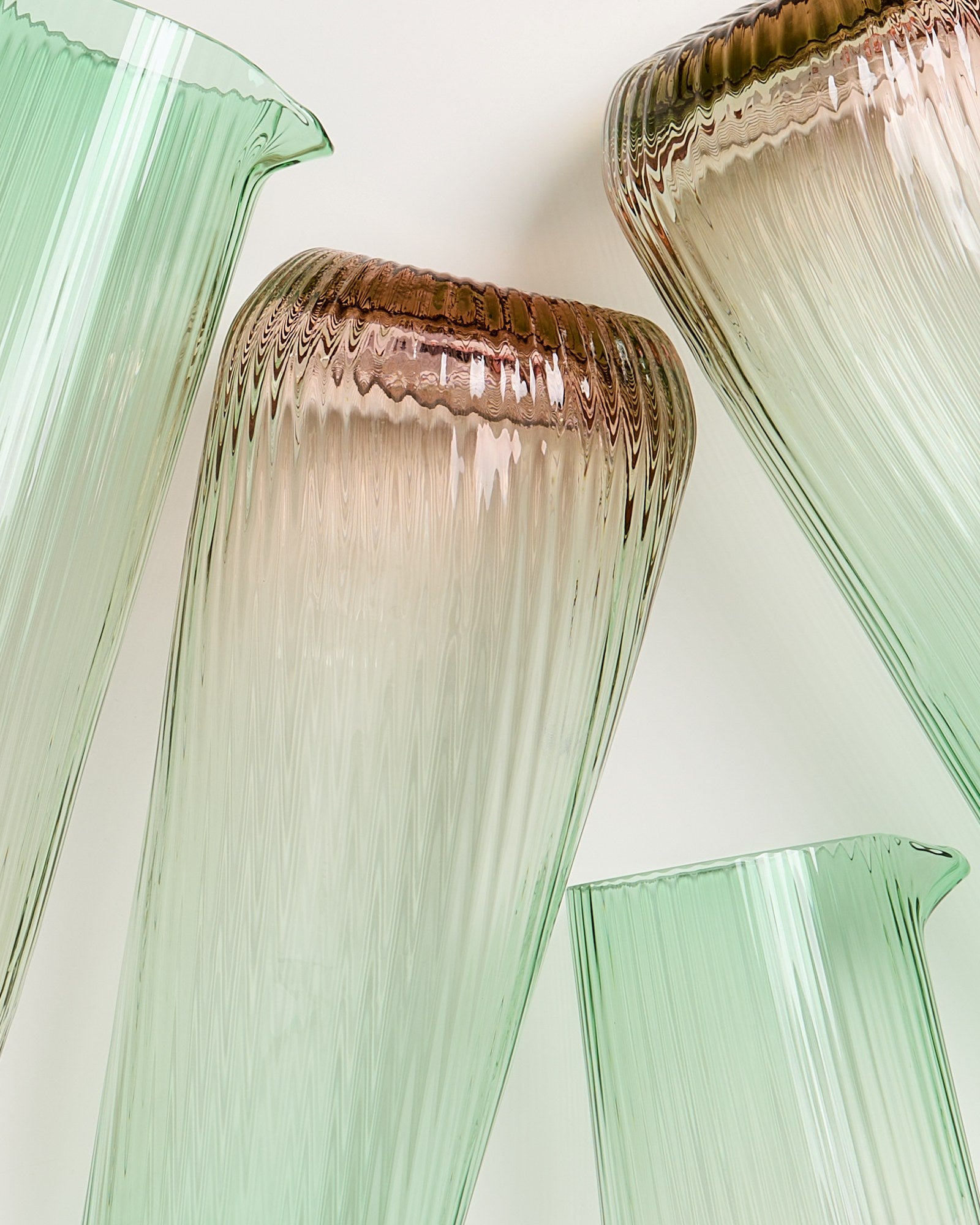 Grüne und braune Glasvasen mit geriffelter Oberfläche auf einem weißen Hintergrund.