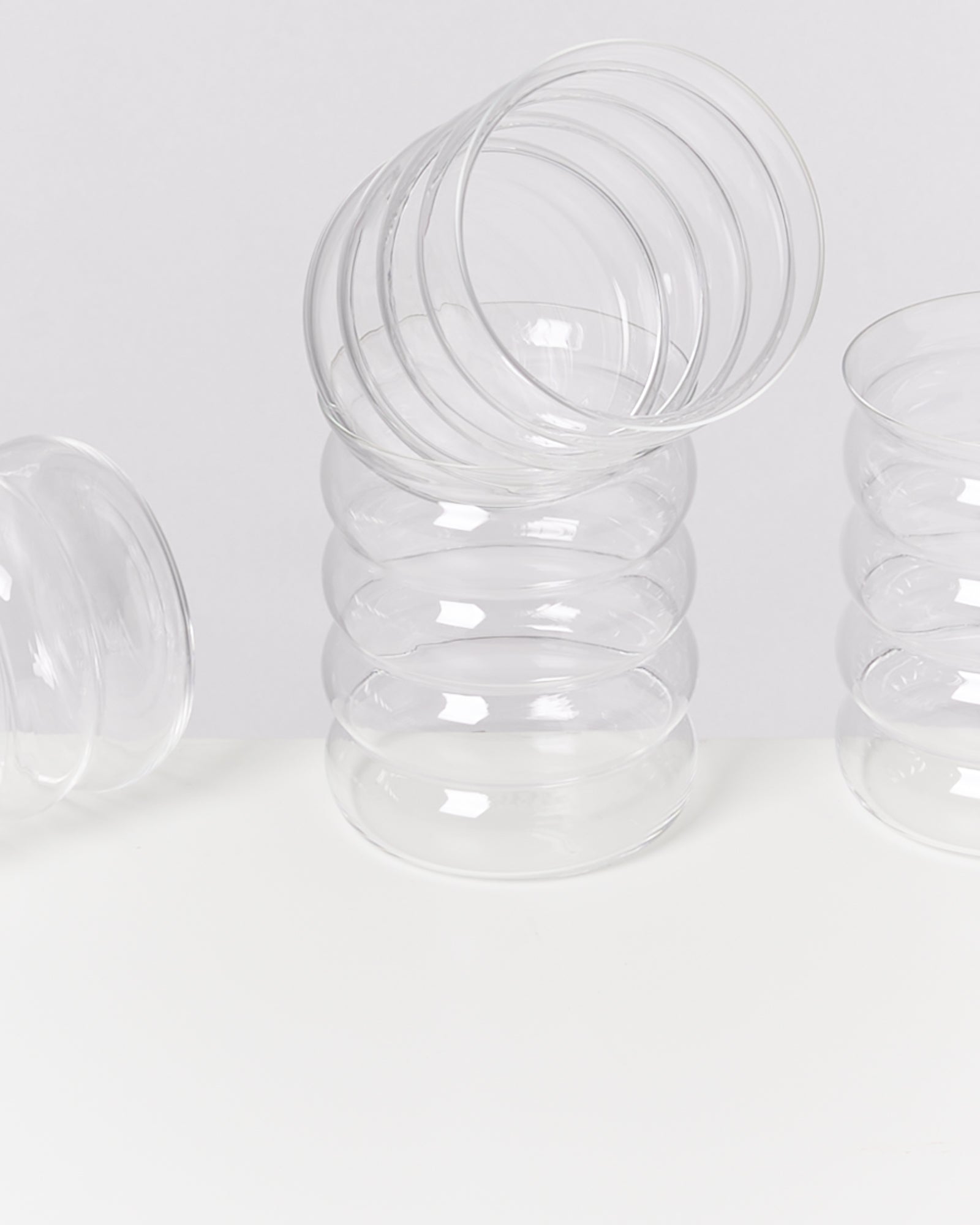 Ein Stapel transparenter, gerippter Gläser auf einer weißen Oberfläche.