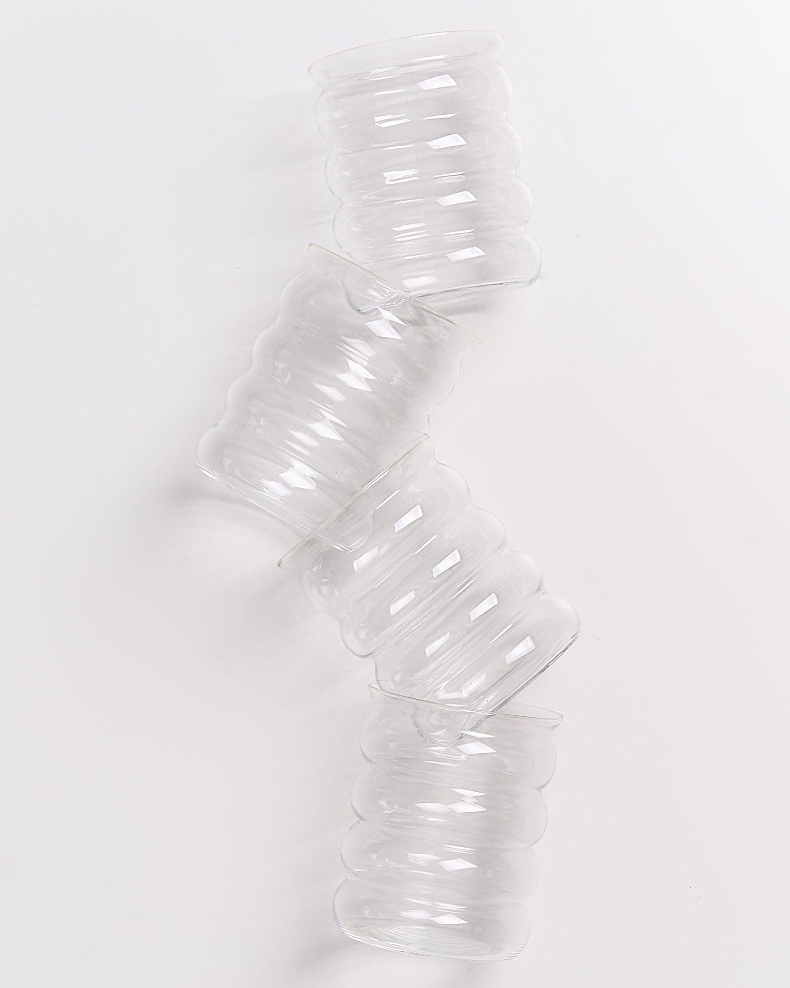 Vier ineinander gestapelte, transparent gewellte Gläser auf weißem Hintergrund.