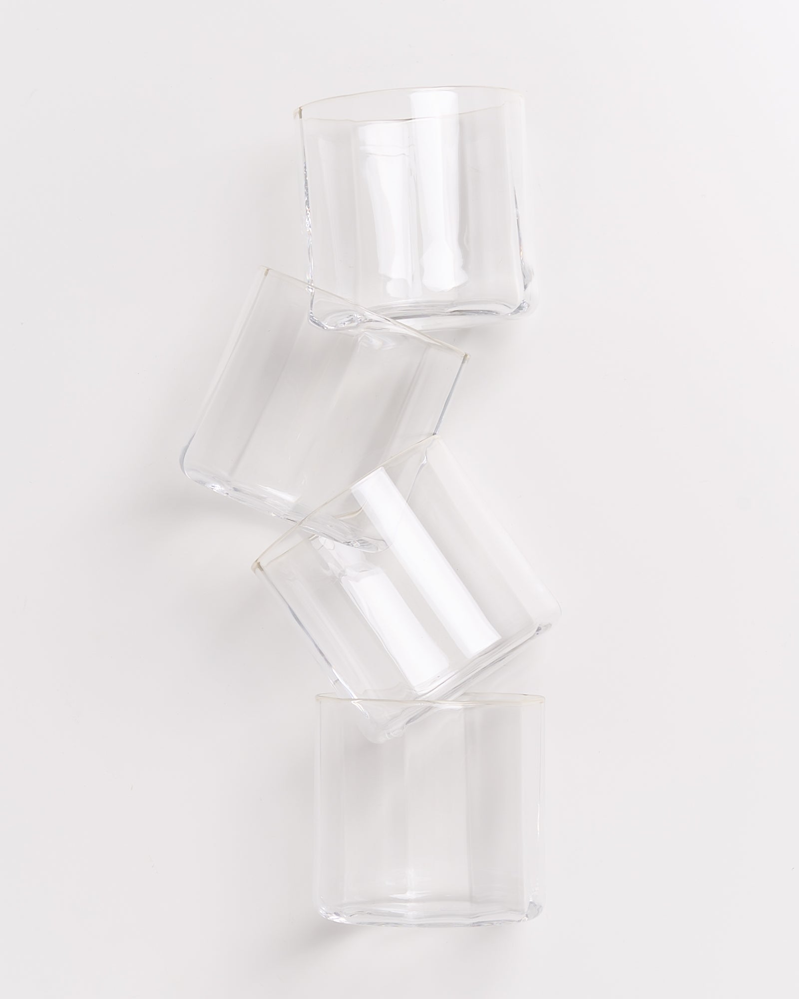 Vier gestapelte, transparente Gläser auf weißem Hintergrund.