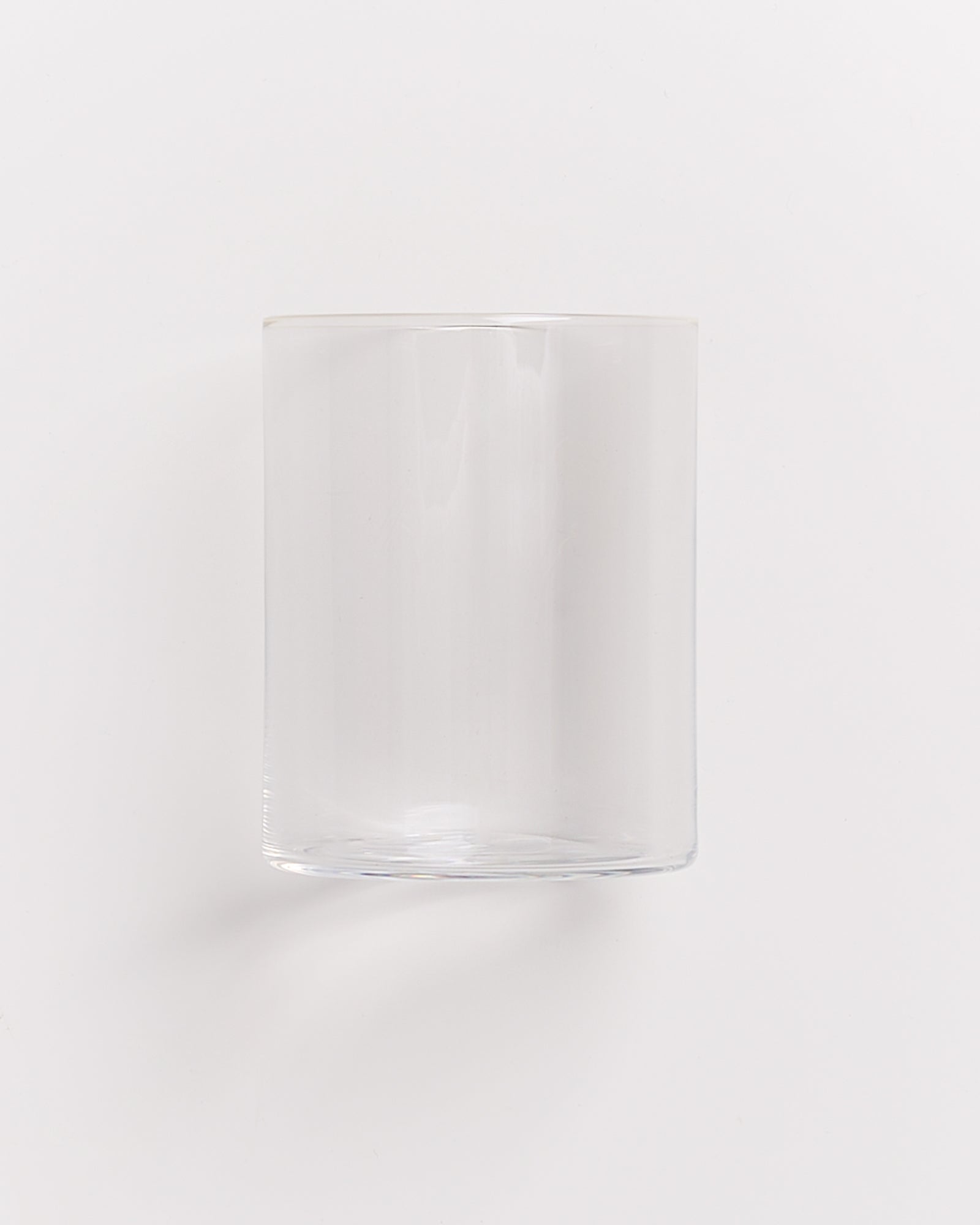 Ein leerer, durchsichtiger Glaszylinder vor weißem Hintergrund.