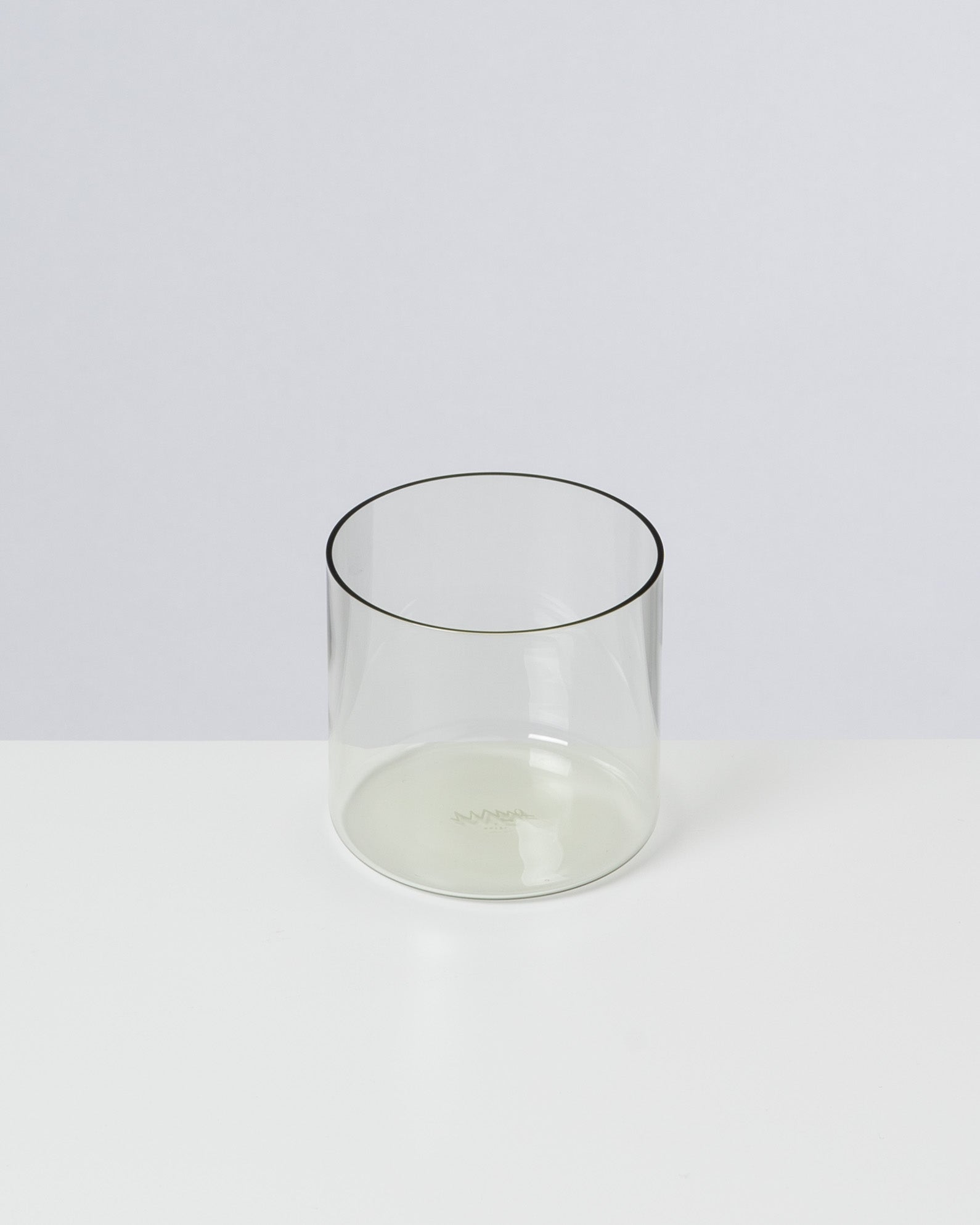 Ein transparentes, zylindrisches Glas steht auf einer weißen Oberfläche.